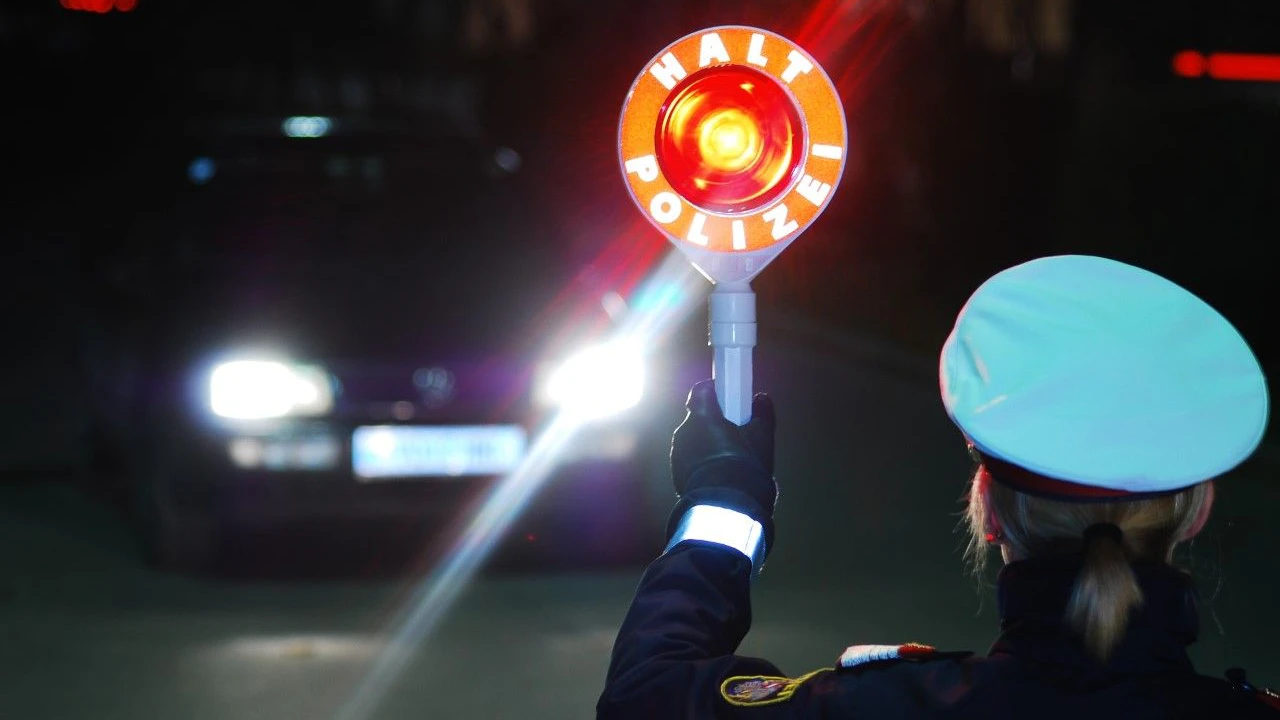 Eine Polizeibeamtin fordert einen Pkw-Lenker zum Anhalten auf. Symbolbild.