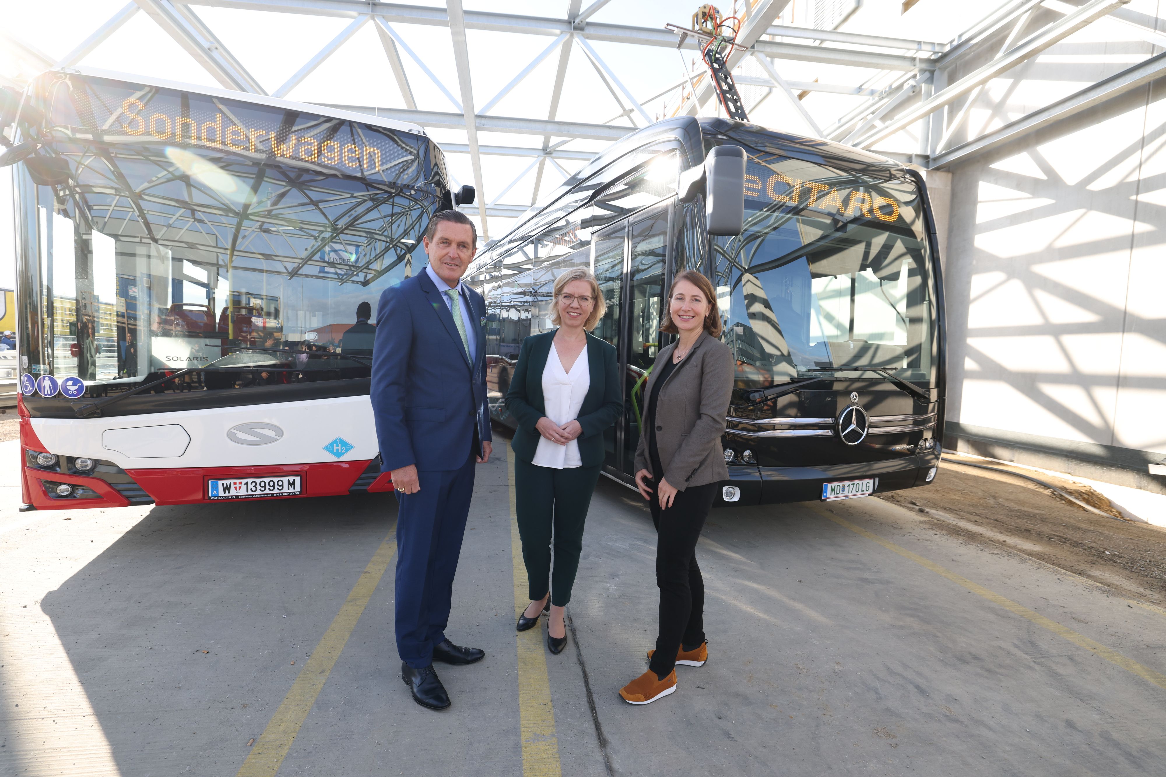 Öffi-Stadtrat Peter Hanke, Klimaschutzministerin Leonore Gewessler und Gudrun Senk, Geschäftsführerin Wiener Linien (v.l.) vor den beiden neuen Bustypen: links der Wasserstoff-Bus und rechts der Elektro-Bus.