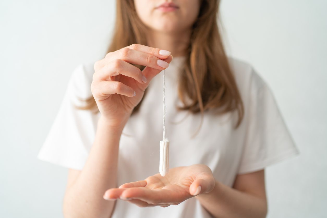A tampon in women's hands on a white background. Period of menstruation. Protection during menstruation.