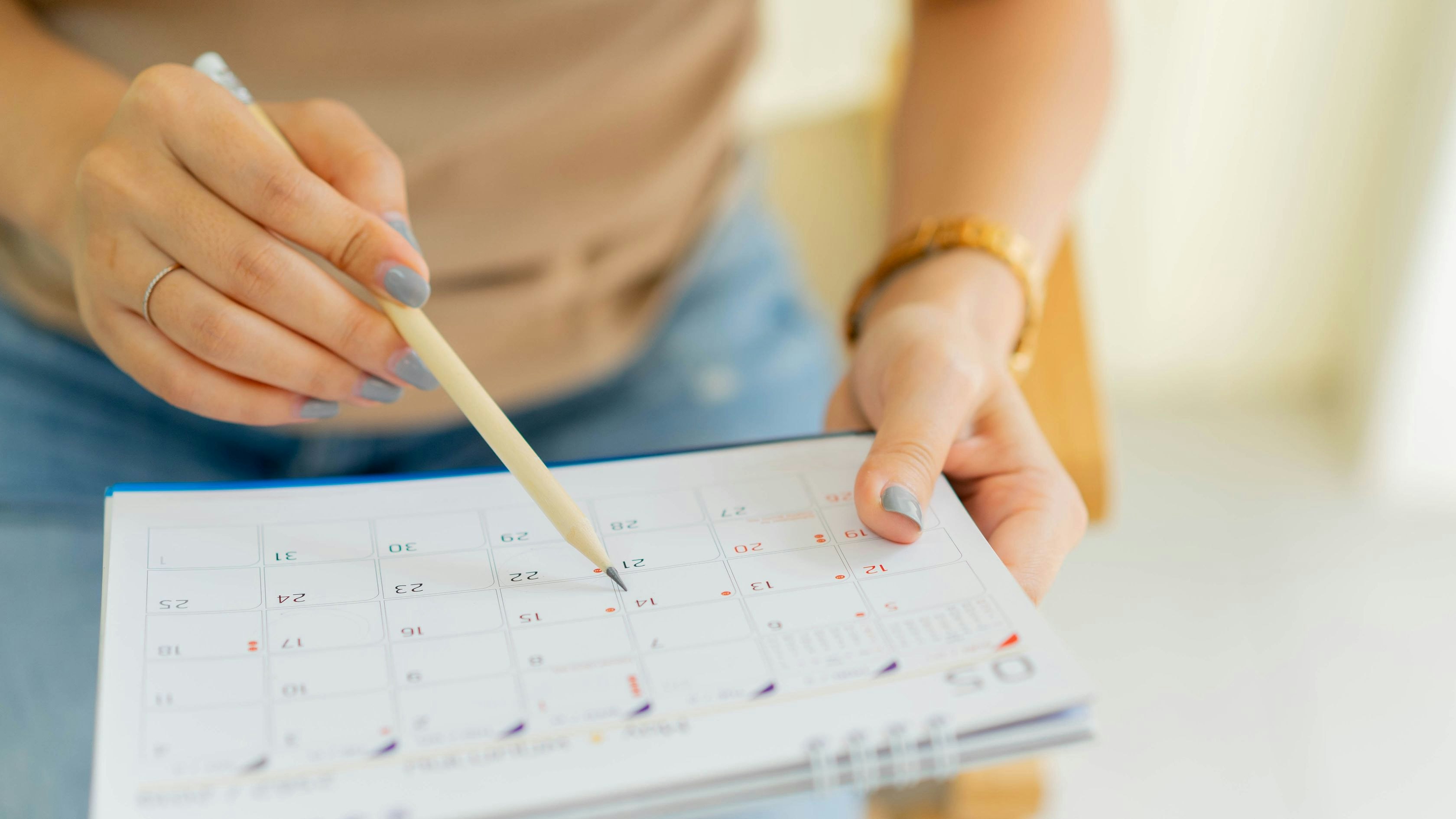close up on senior employee woman hand using pen to writing schedule on calendar to make appointment meeting or manage timetable each day at house for work from home concept