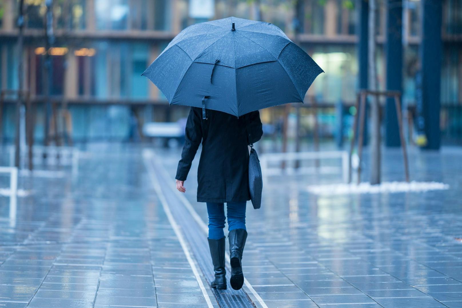 Eine Frau mit riesigem Regenschirm stapft bei miesem Wetter durch Wien. Symbolbild.