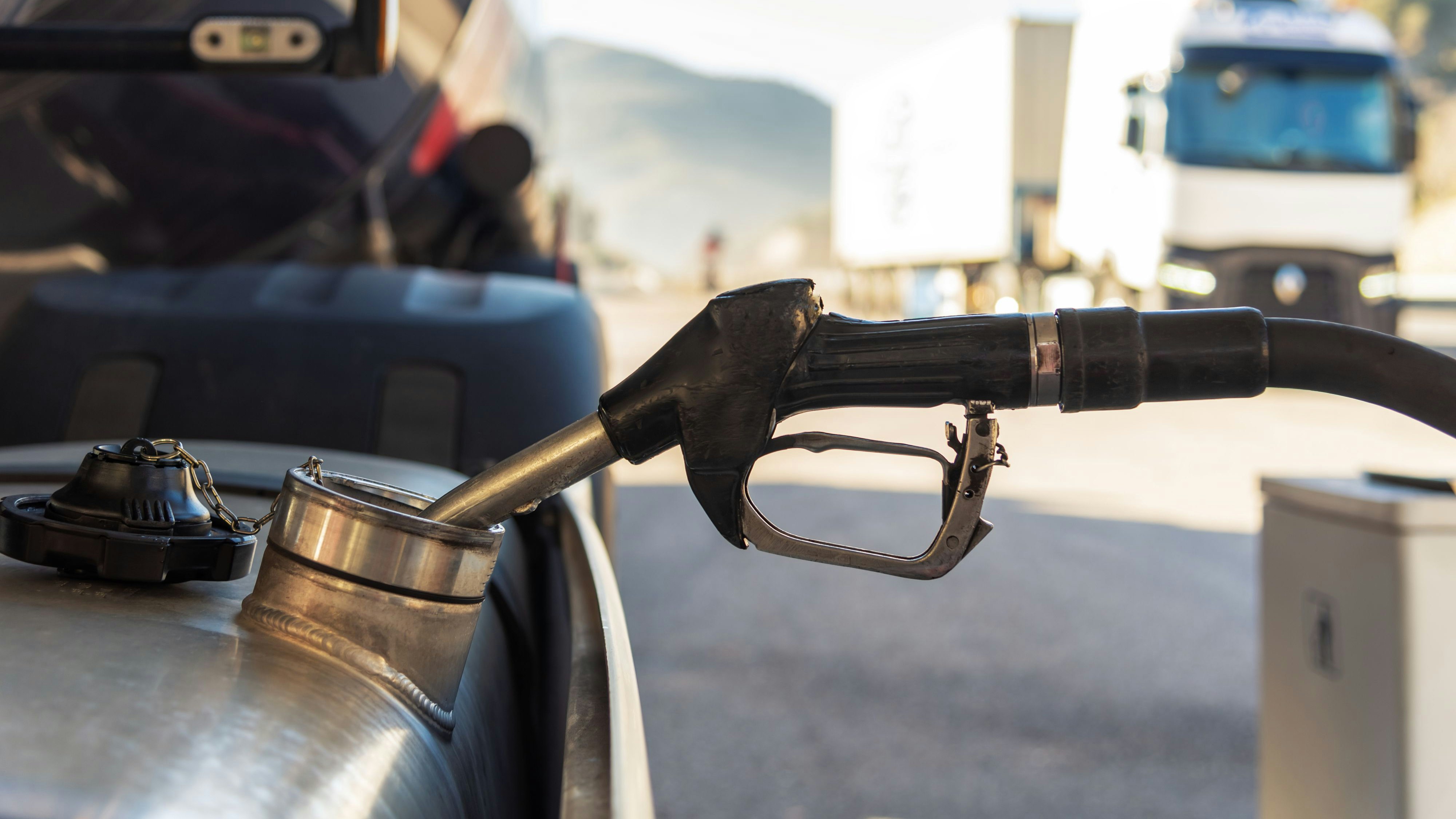 Truck refueling diesel at a highway gas station, close-up of the nozzle inserted in the vehicle's tank.