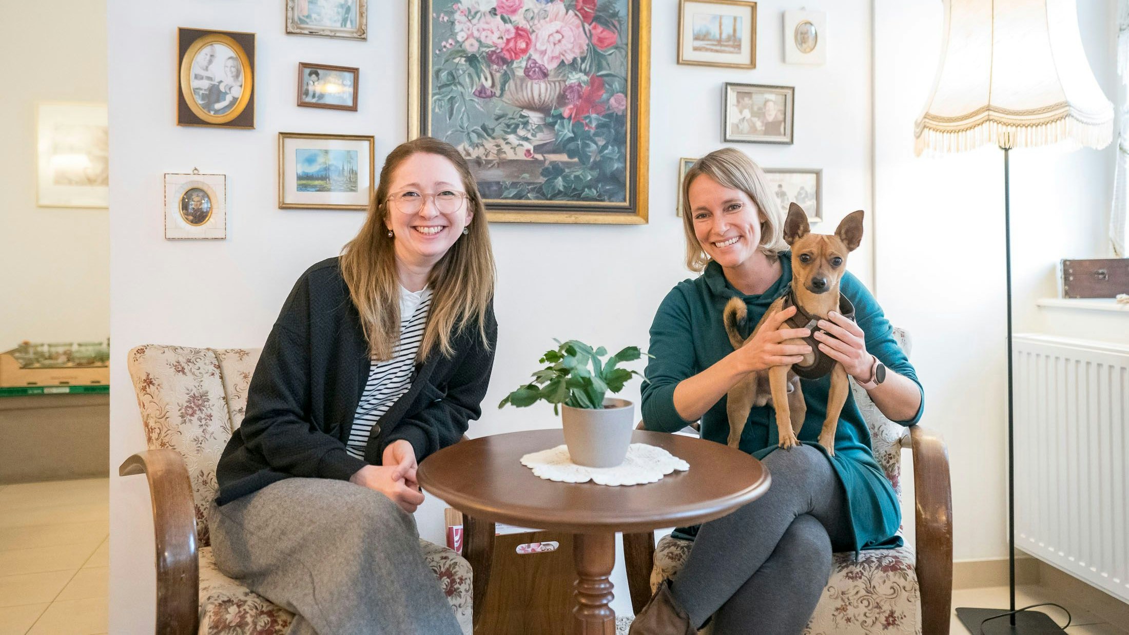 Luise Steinkellner (41), Daniela Weinholtz (42) und Kobi, der kleine Wachhund in der "qualitätszeit". Den "Trainingsraum für Internet und Technik" haben sie mit analogen Telefonen mit Wählscheibe, alten Radios und anderen Dingen eingerichtet, die ältere Leute nett finden oder noch von früher kennen.