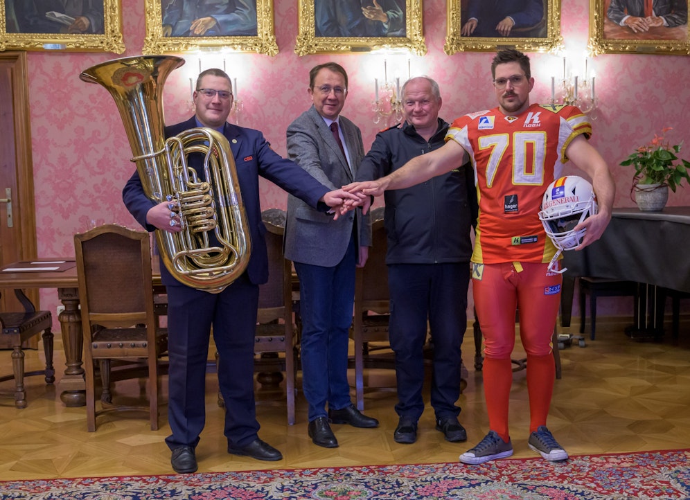 Bürgermeister Matthias Stadler, Lukas Halbartschlager von Eisenbahner-Blasmusik, Abschnittsfeuerwehrkommandant Franz Klampfl und Footballspieler MIchael Derfler von Generali Invaders kämpfen Hand in Hand für Aufklärungsarbeit zum Impfstatus.