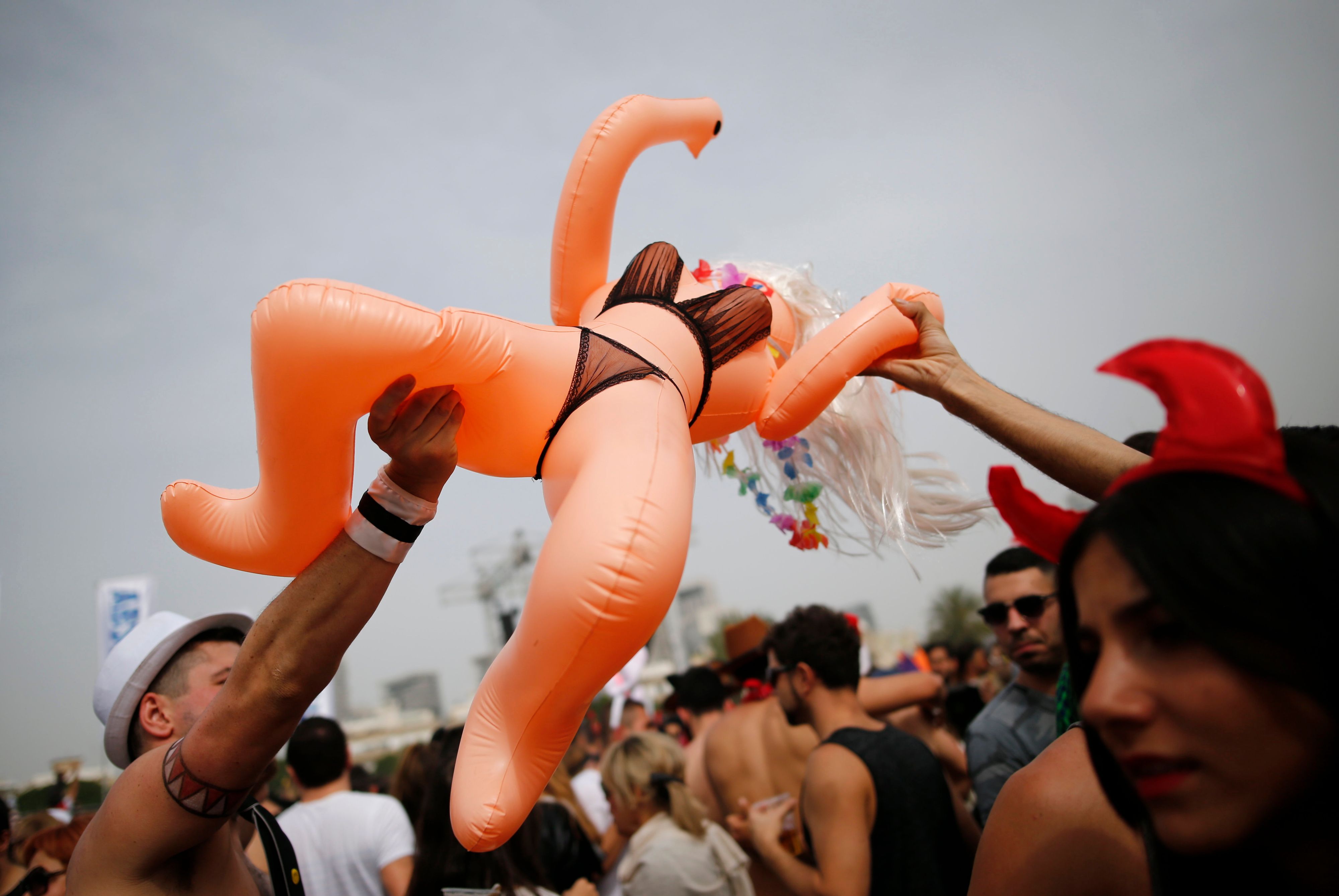 People wearing costumes lift an inflatable sex doll in the air during a street party marking the Jewish holiday of Purim in Tel Aviv March 25, 2016. Purim is a celebration of the Jews' salvation from genocide in ancient Persia, as recounted in the Book of Esther. REUTERS/Amir Cohen
