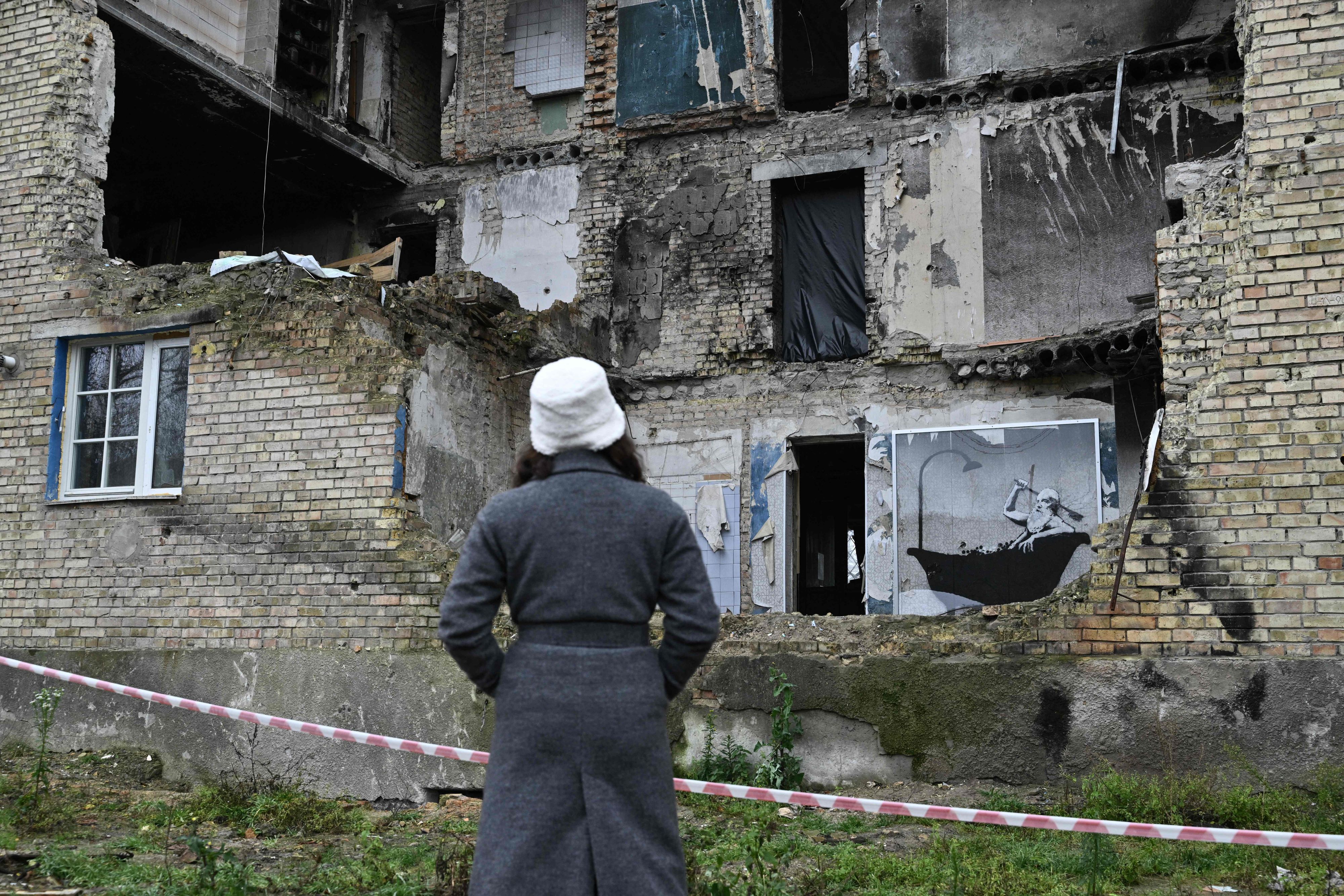 Download von www.picturedesk.com am 17.11.2022 (09:27).  A woman looks at a graffiti made by Banksy on the wall of a heavily damaged building in the Gorenka village, near Kyiv, amid the Russian invasion of Ukraine. (Photo by Genya SAVILOV / AFP) / RESTRICTED TO EDITORIAL USE - MANDATORY MENTION OF THE ARTIST UPON PUBLICATION - TO ILLUSTRATE THE EVENT AS SPECIFIED IN THE CAPTION - 20221116_PD10384 - Rechteinfo: Rights Managed (RM) Nur für redaktionelle Nutzung! Werbliche Nutzung erfordert Freigabe: bitte schicken Sie uns eine Anfrage.