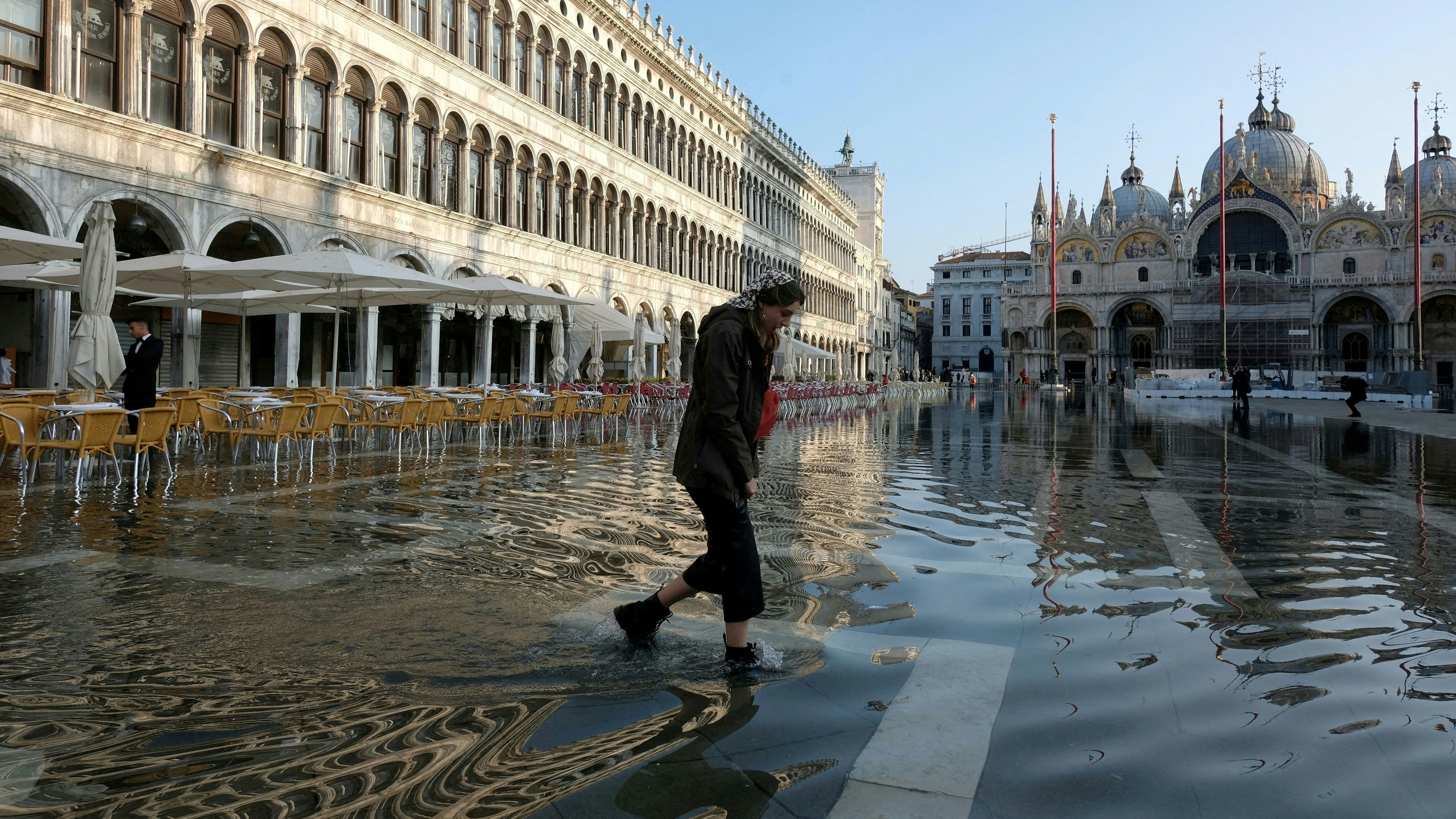 FILE PHOTO: A woman wades through water in flooded St. Mark's Square during seasonal high water in Venice, Italy, November 21, 2022. REUTERS/Manuel Silvestri/File Photo