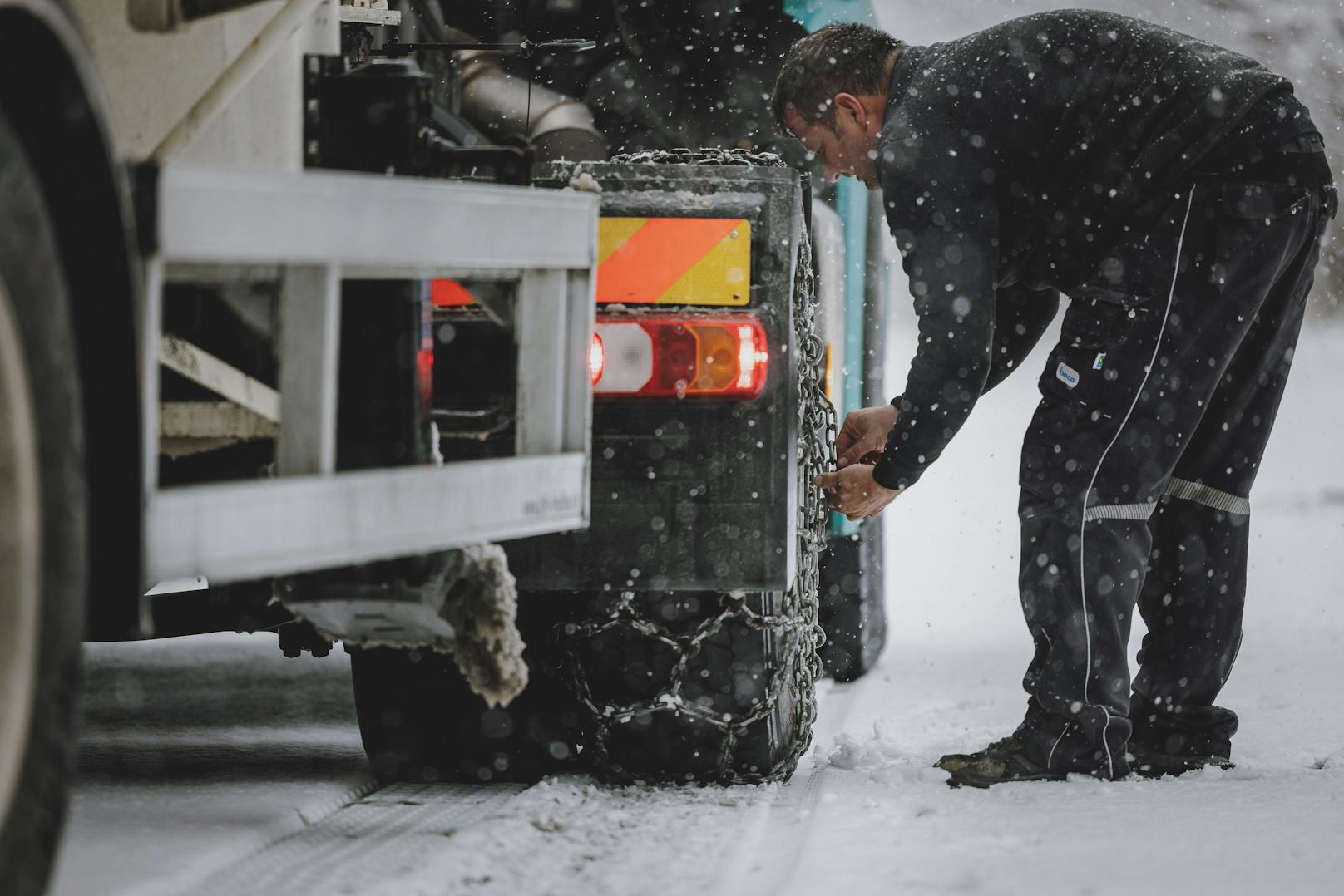 Ein Lkw-Fahrer montiert Schneeketten an seinem Lastwagen, aufgenommen am 22. November 2022 in Kaprun.