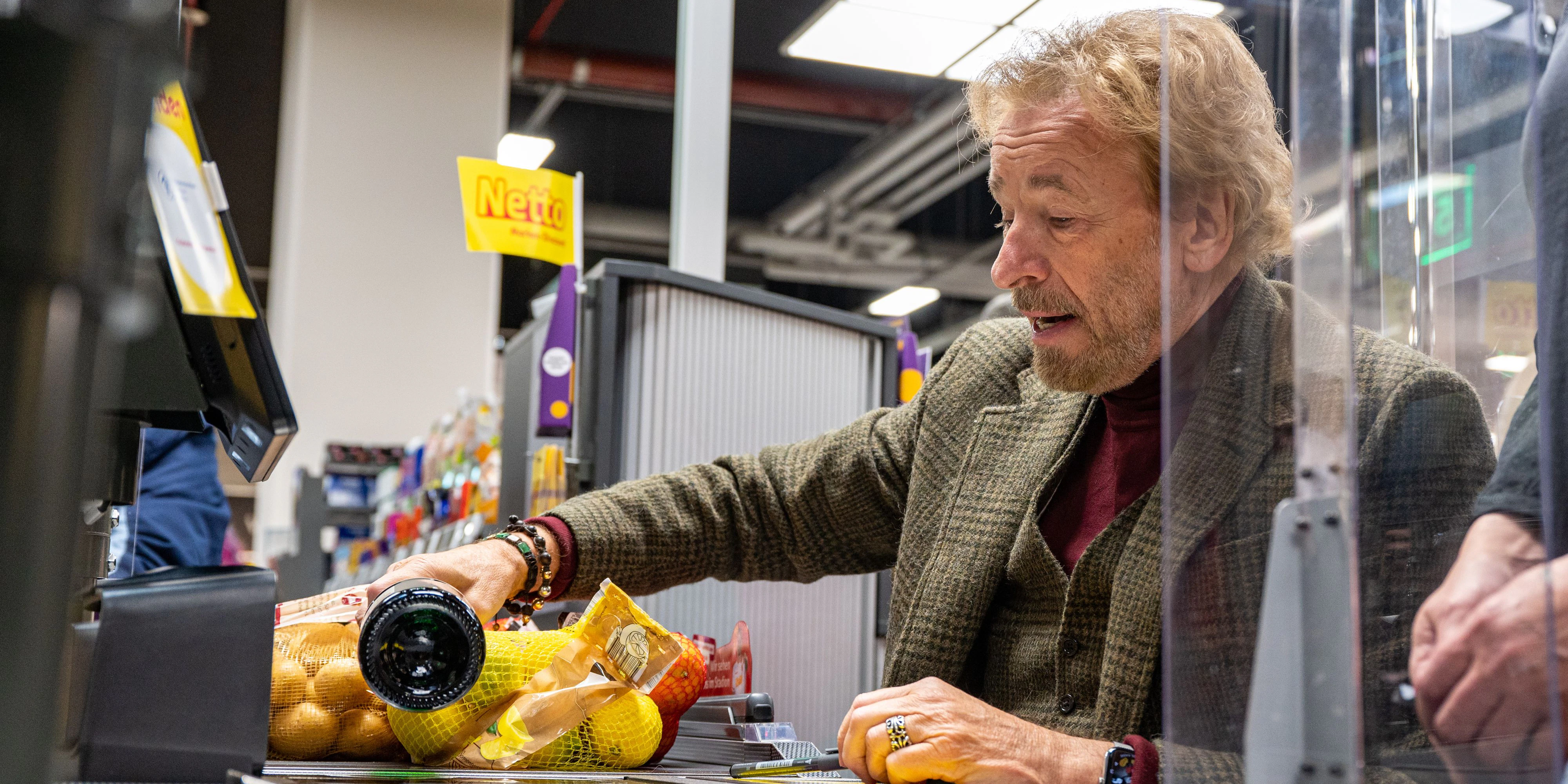 Thomas Gottschalk sitzt an der Kassa im Supermarkt.