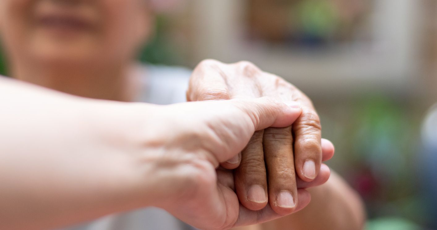 Caregiver, carer hand holding elder hand in hospice care. Philanthropy kindness to disabled concept.