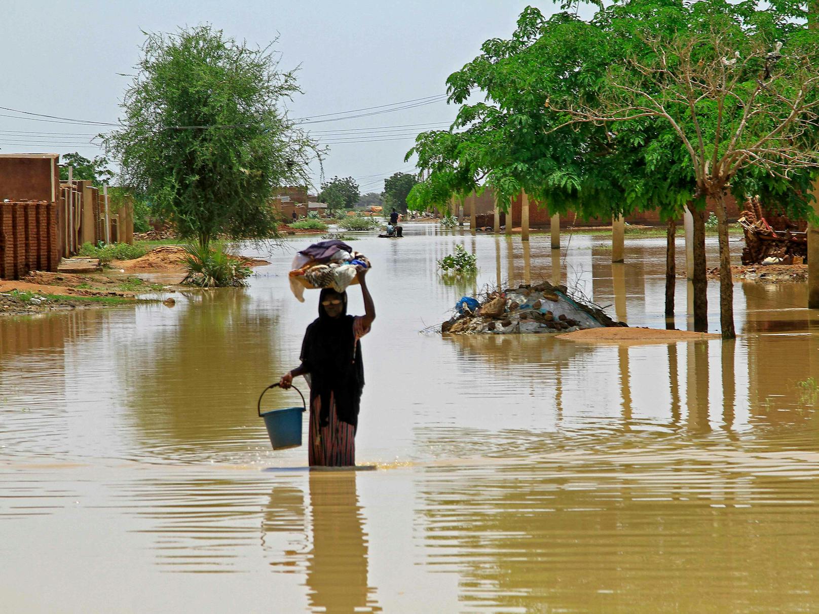 Eine Frau watet im Dorf Makaylab, etwa 400 Kilometer nördlich der Hauptstadt Khartum, durch Hochwasser. Seit Beginn der verheerenden Regenzeit sind Tausende sudanesischer Familien obdachlos geworden.