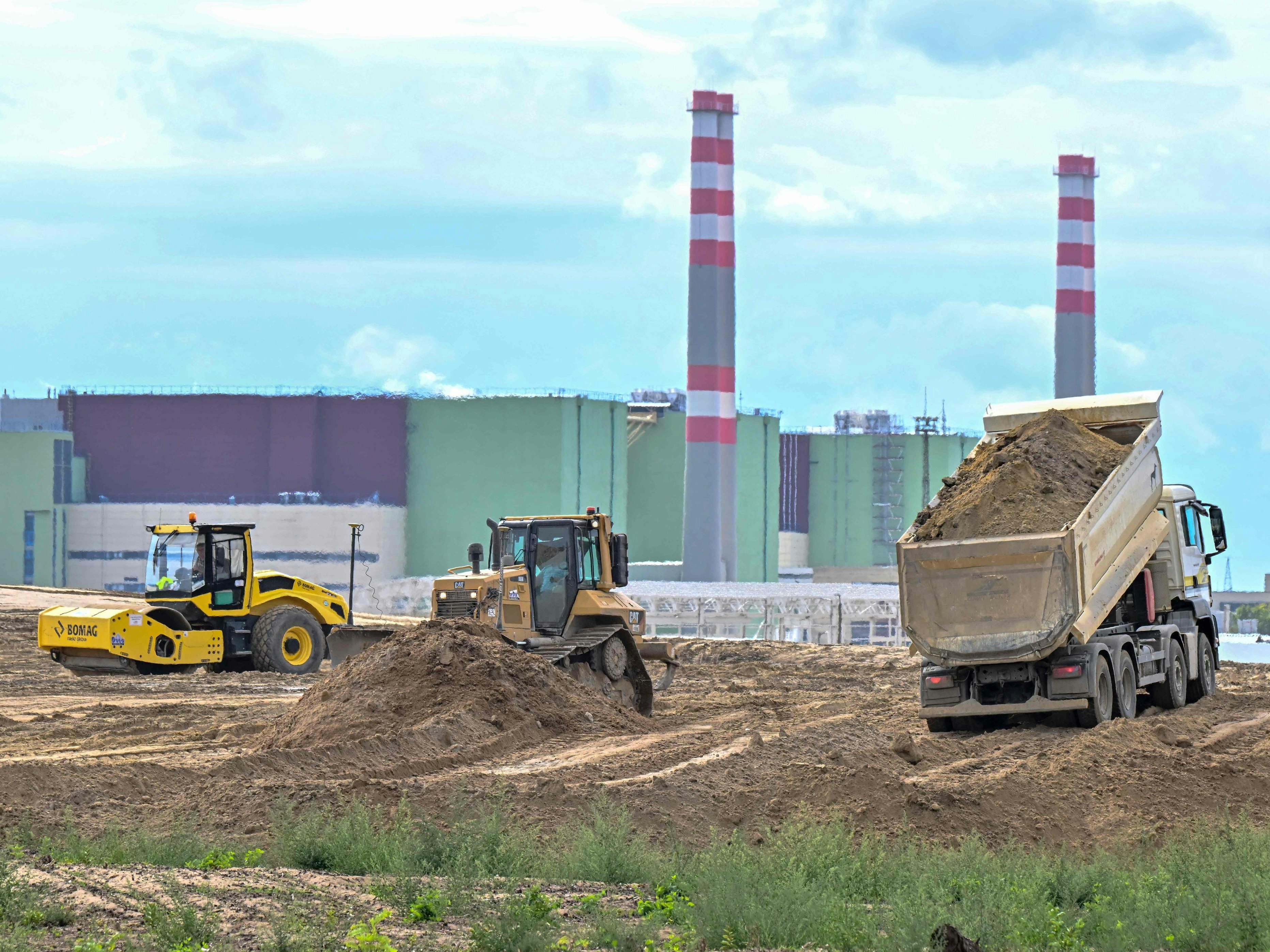 Download von www.picturedesk.com am 30.11.2022 (12:42).  Trucks and excavators work in the area of the Paks Nuclear Power Plant to prepare the new Paks II construction works on September 10, 2022, in Paks, southern Hungary, as the buildings of Paks I nuclear power plant are visible in the background. - The Hungarian 'National Atomic Energy Agency' (OAH) issued the construction permit for the Paks II reactor building of block No.5 for the expansion of the nuclear power plant at the end of August 2022. The construction works started in the first week of September and the workers are currently carrying out the earthworks. (Photo by ATTILA KISBENEDEK / AFP) - 20220910_PD8355 - Rechteinfo: Rights Managed (RM) Nur für redaktionelle Nutzung! Werbliche Nutzung erfordert Freigabe: bitte schicken Sie uns eine Anfrage.