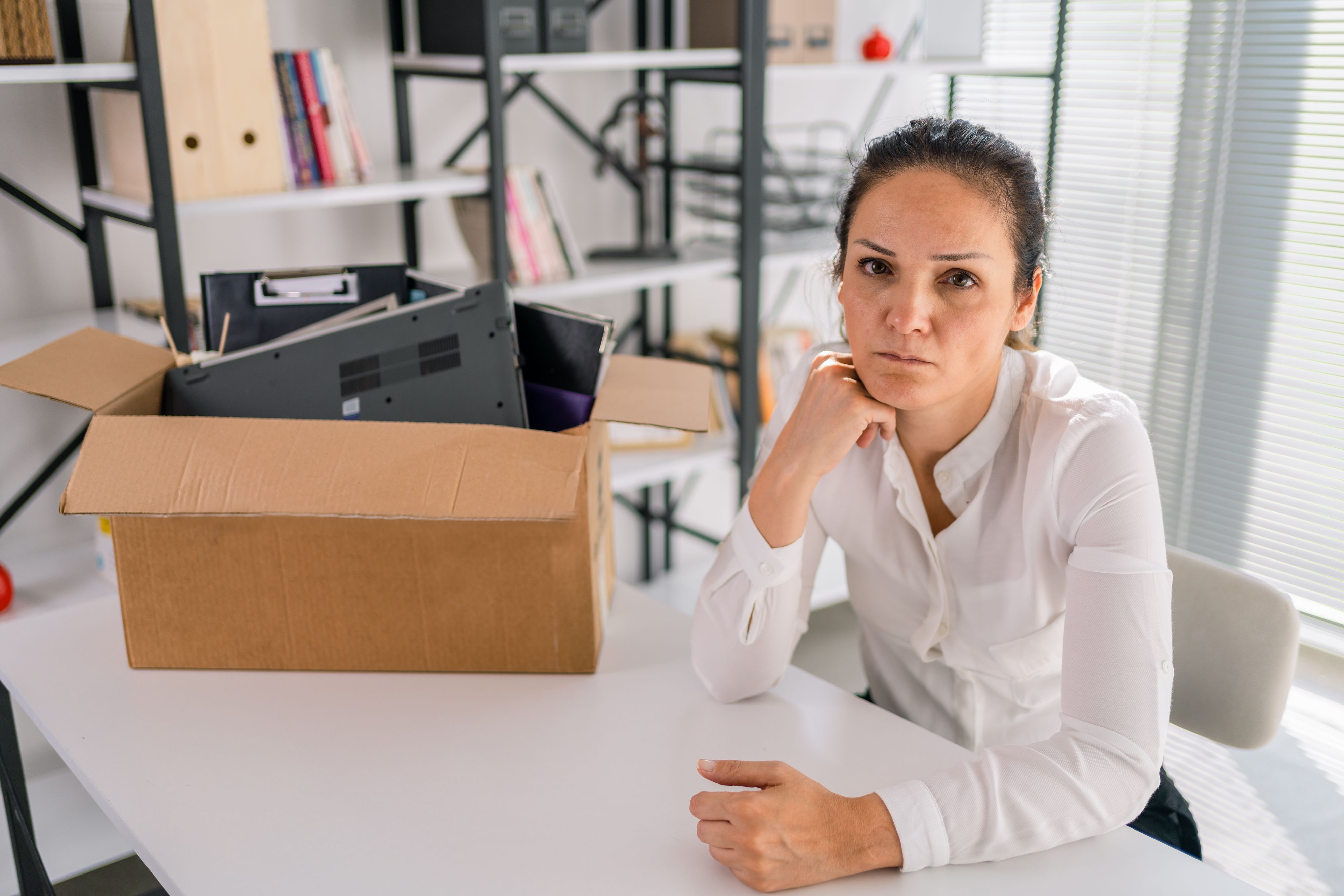 Taking a gap. Concentrated involved melancholy employee standing and packing the box with his belongings while leaving the company and expressing sadness