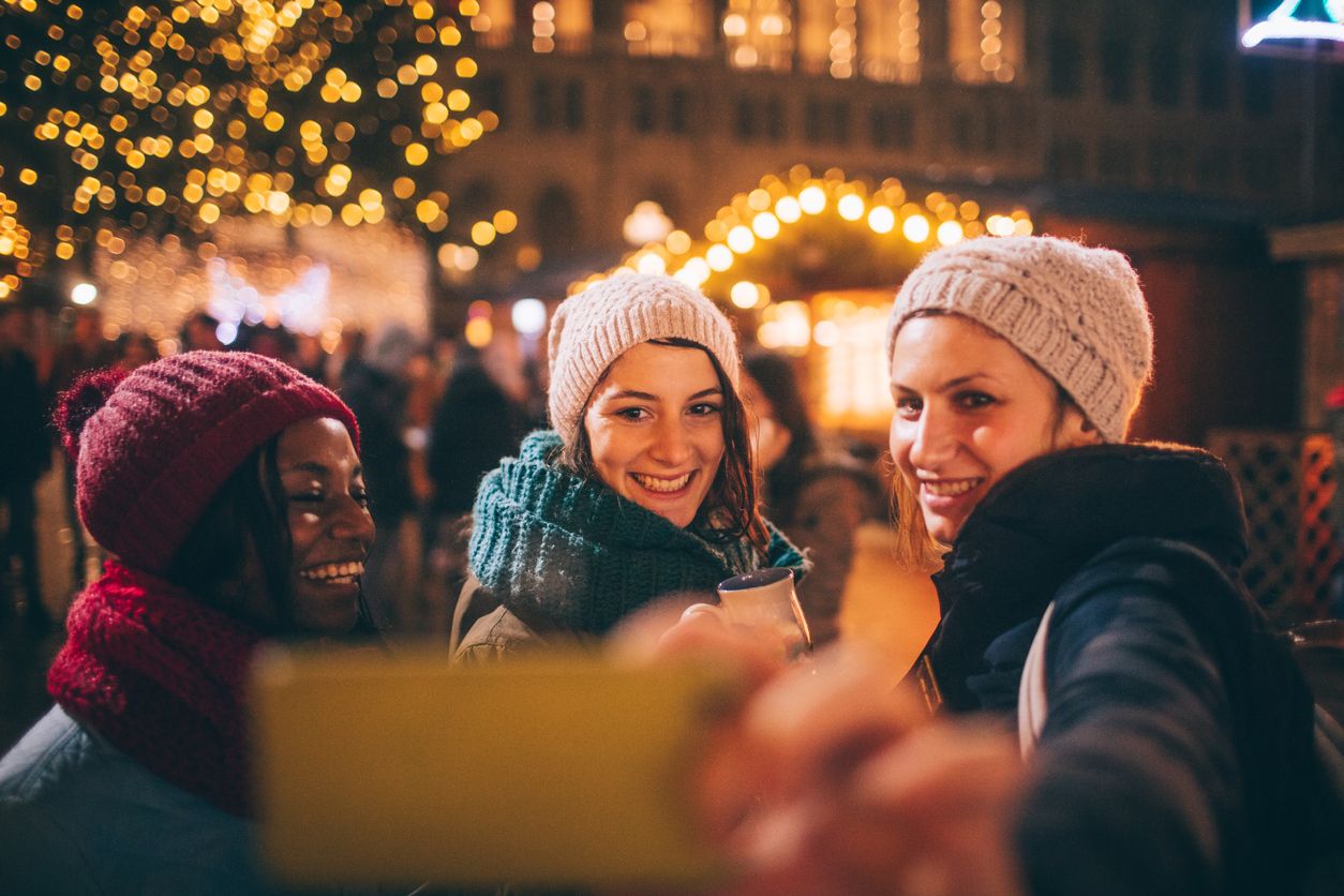 Photo of a cheerful friends taking a selfie to capture a memory from Christmas Market