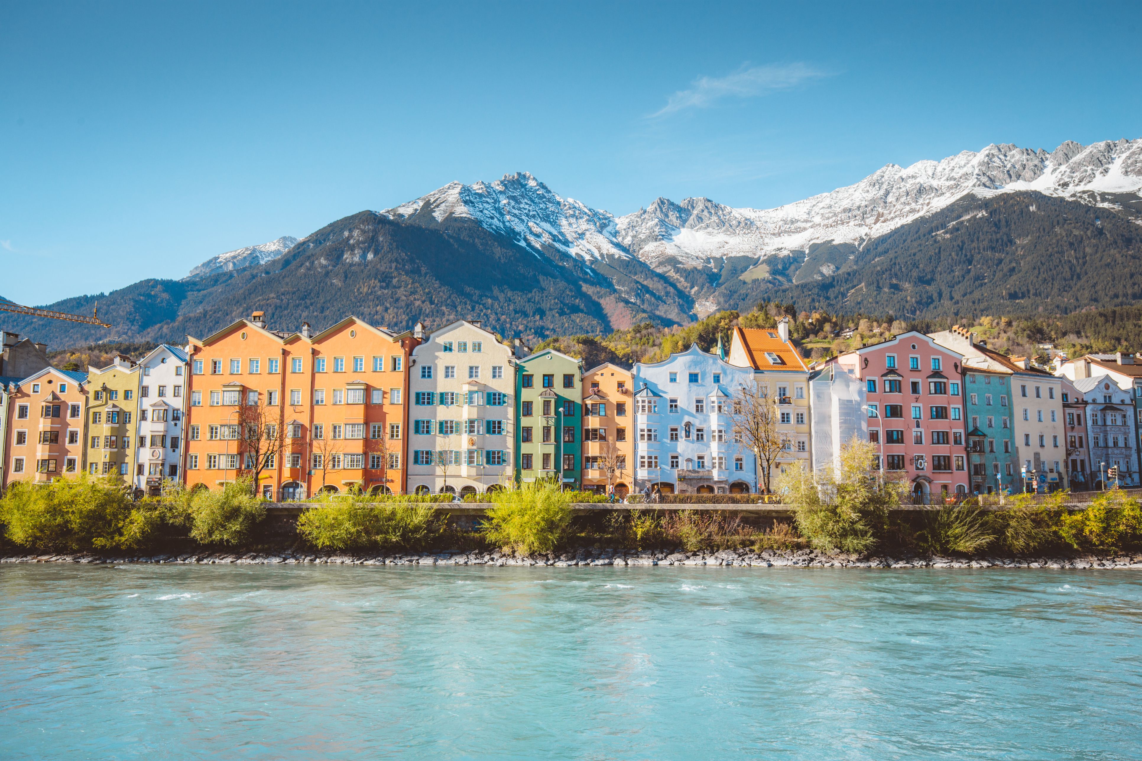 Panoramic view of the historic city center of Innsbruck with colorful houses along Inn river and famous Austrian mountain summits in the background in beautiful evening light at sunset, Tyrol, Austria