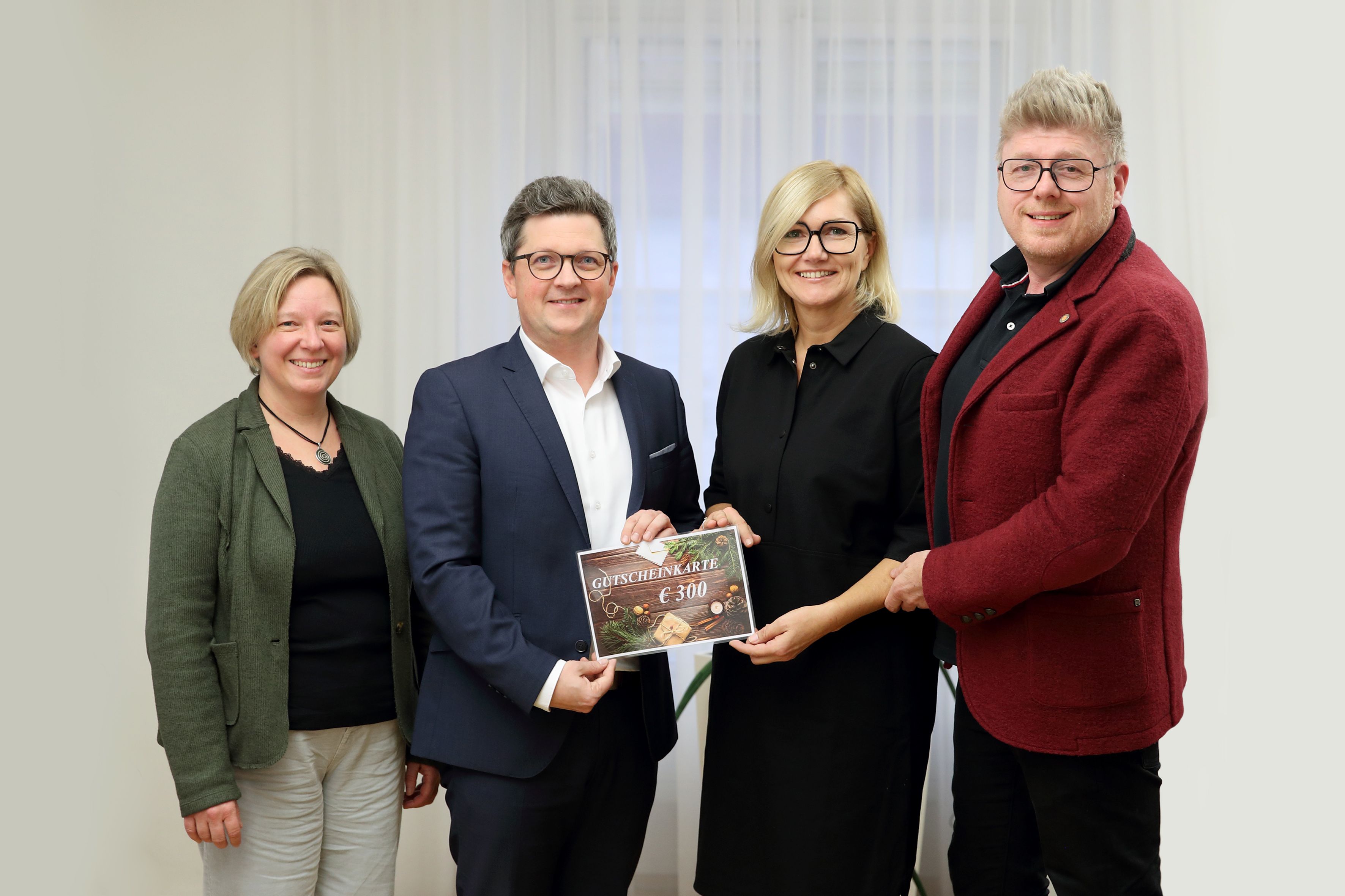Michael Lindner (2.v.l.) und Sozialarbeiterin Katharina Etschmann (l.) überreichten den Pflegeeltern Angelika und Christian S. den Gutschein.