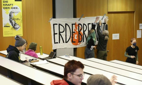Aktivistinnen befestigen ein "Erde Brennt"-Plakat im besetzten Hörsaal.