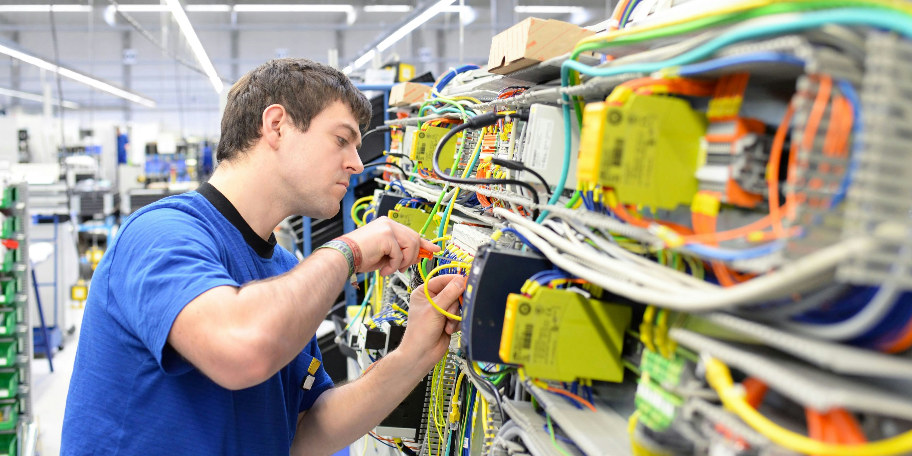 young operator assembles machine in a modern high tech factory - production of switch cabinets for industrial plant
