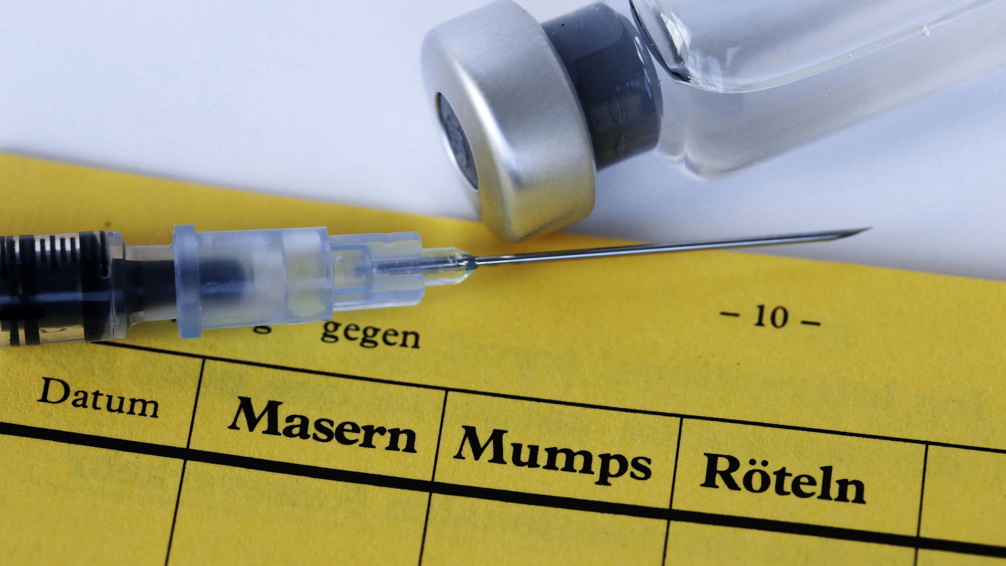Vaccination against measles, mumps and rubella with vaccination card, syringe and vaccine