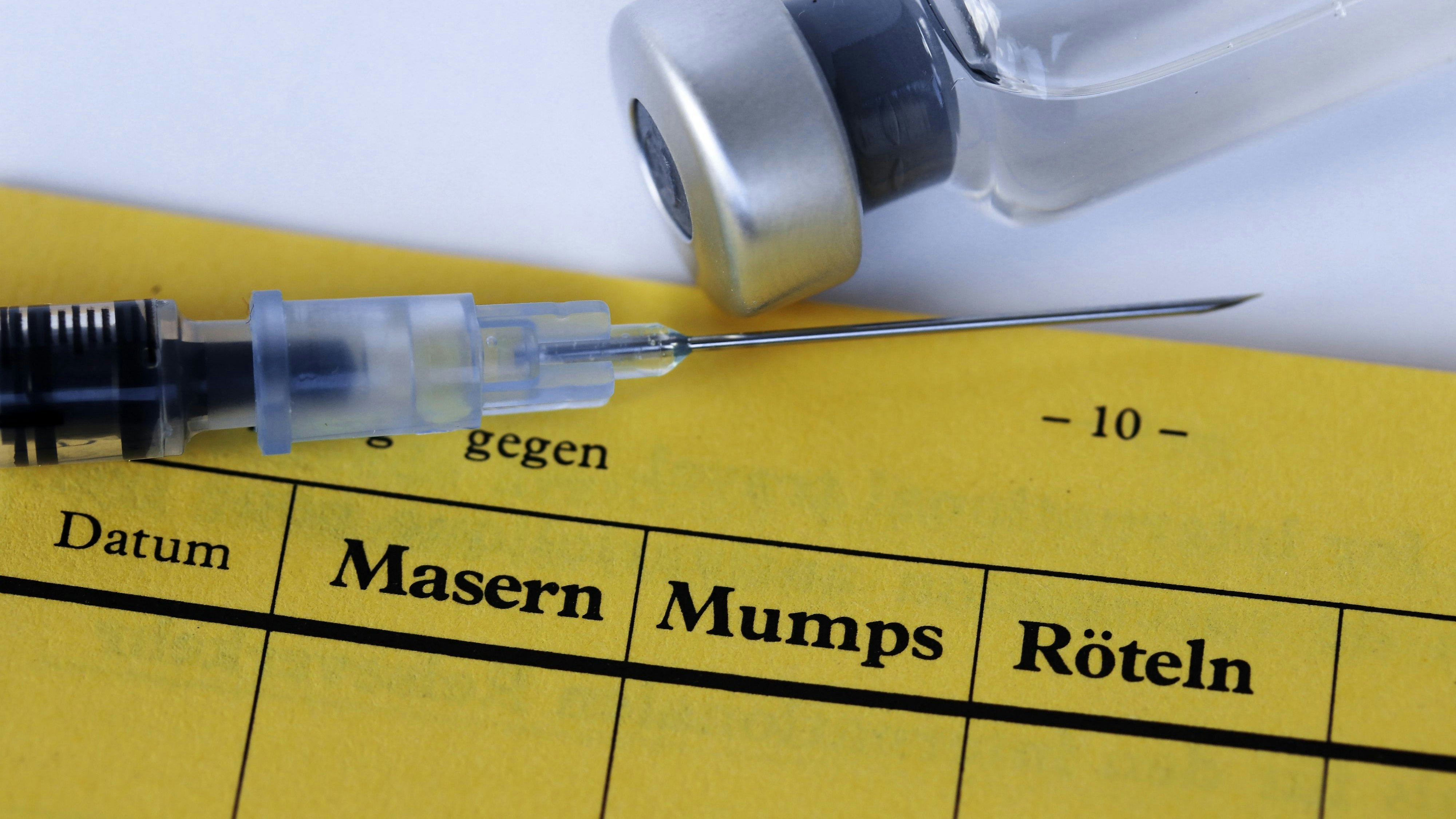 Vaccination against measles, mumps and rubella with vaccination card, syringe and vaccine