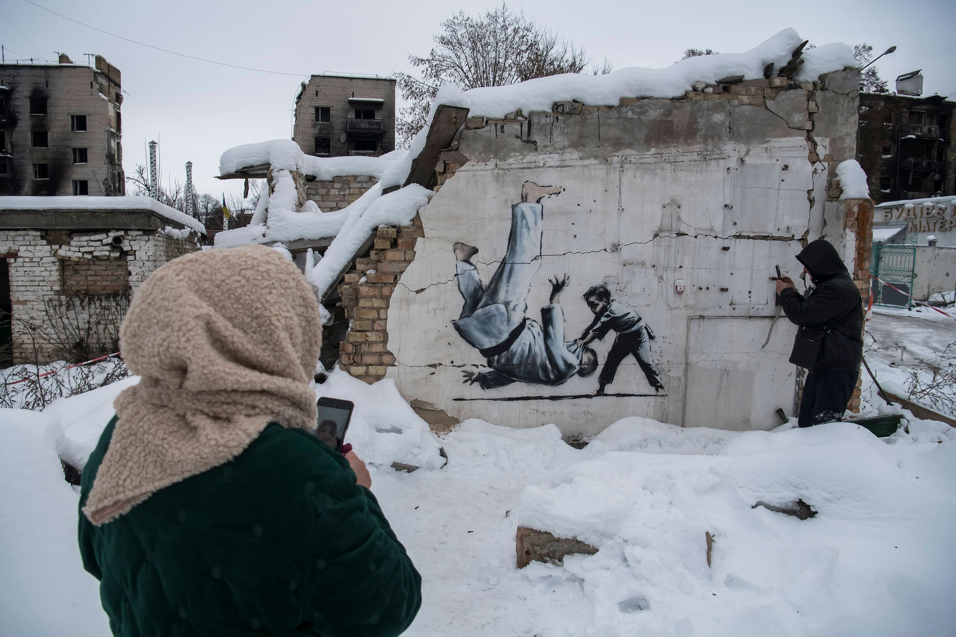 Graffiti Made By Banksy In The Borodianka And Hostomel Towns Near Kyiv People are making a picture of a Graffiti made by Banksy at the wall of a destroyed residential building among debris covered by snow in Borodianka, Ukraine, on December 6, 2022 Borodianka Ukraine PUBLICATIONxNOTxINxFRA Copyright: xMaxymxMarusenkox originalFilename: musienko-notitle221206_npuq2.jpg 