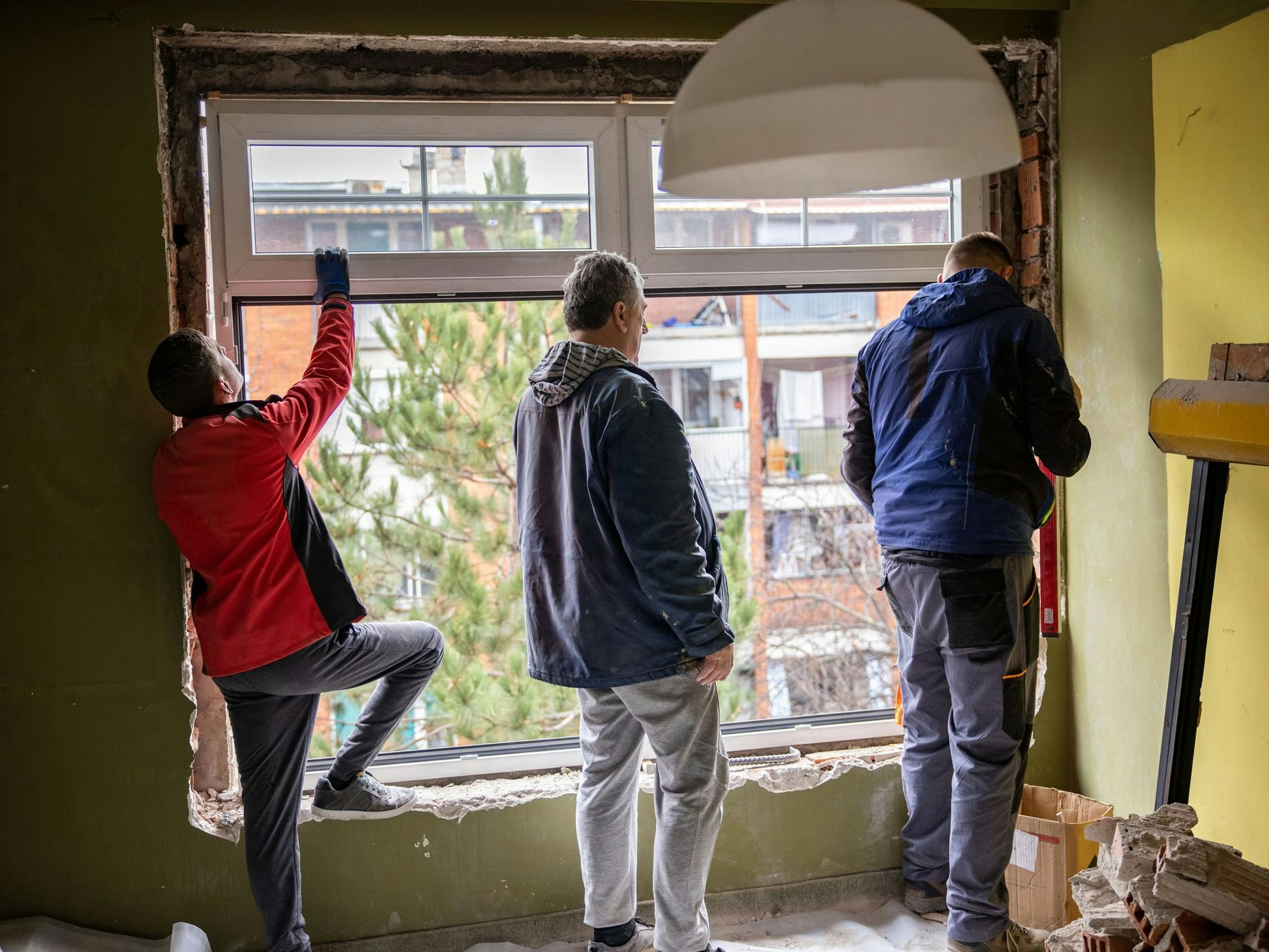 Precisely, group of workers are installing the wide window of the apartment.