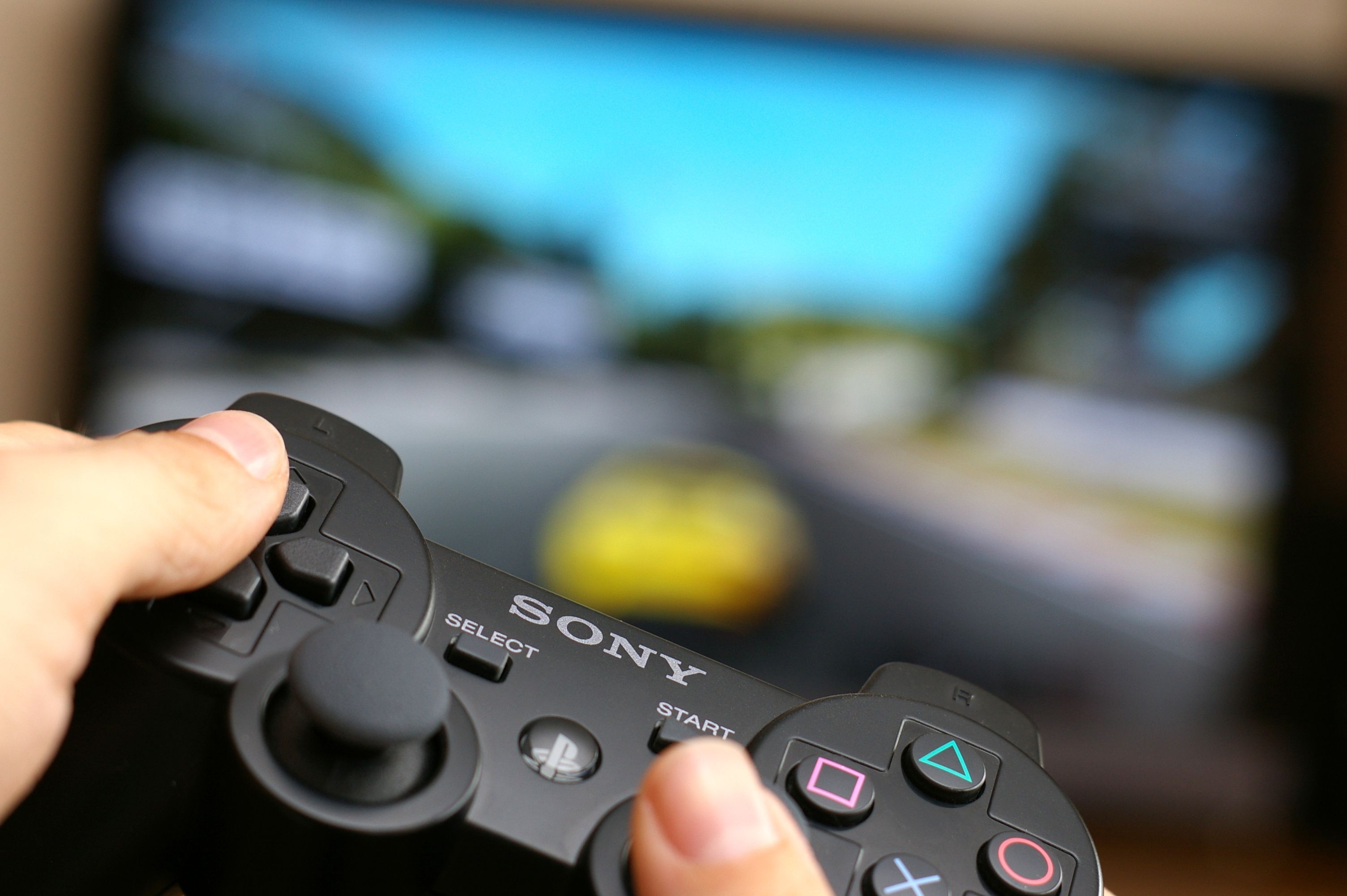 Wejherowo, Poland - July 4, 2011: Man\'s hand holding Sony Dualshock wireless controller while playing Gran Turismo 5 on Playstation 3.