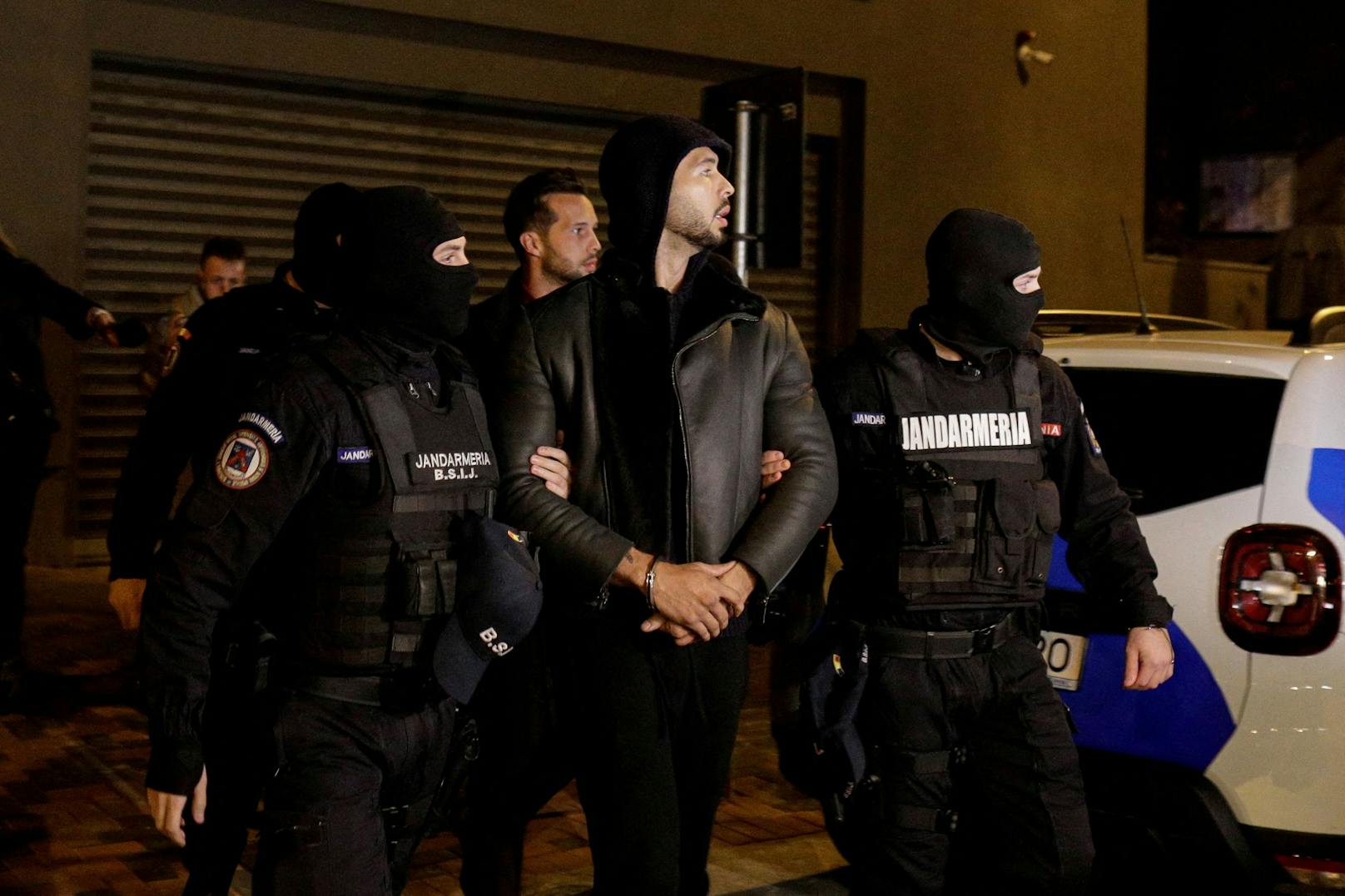 Andrew Tate und Tristan Tate werden von Polizeibeamten vor dem Hauptquartier der Direktion für die Untersuchung von organisierter Kriminalität und Terrorismus in Bukarest (DIICOT) eskortiert.