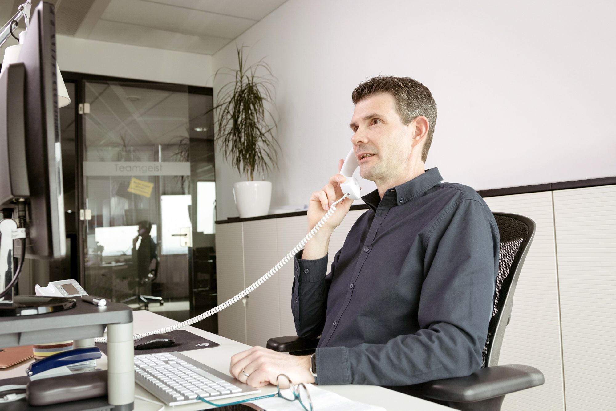 Ein Mitarbeiter beim Telefonieren am Arbeitsplatz.