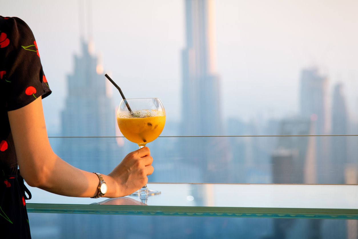 Woman having a drink and enjoying Dubai skyline view of the modern downtown area in United Arab Emirates