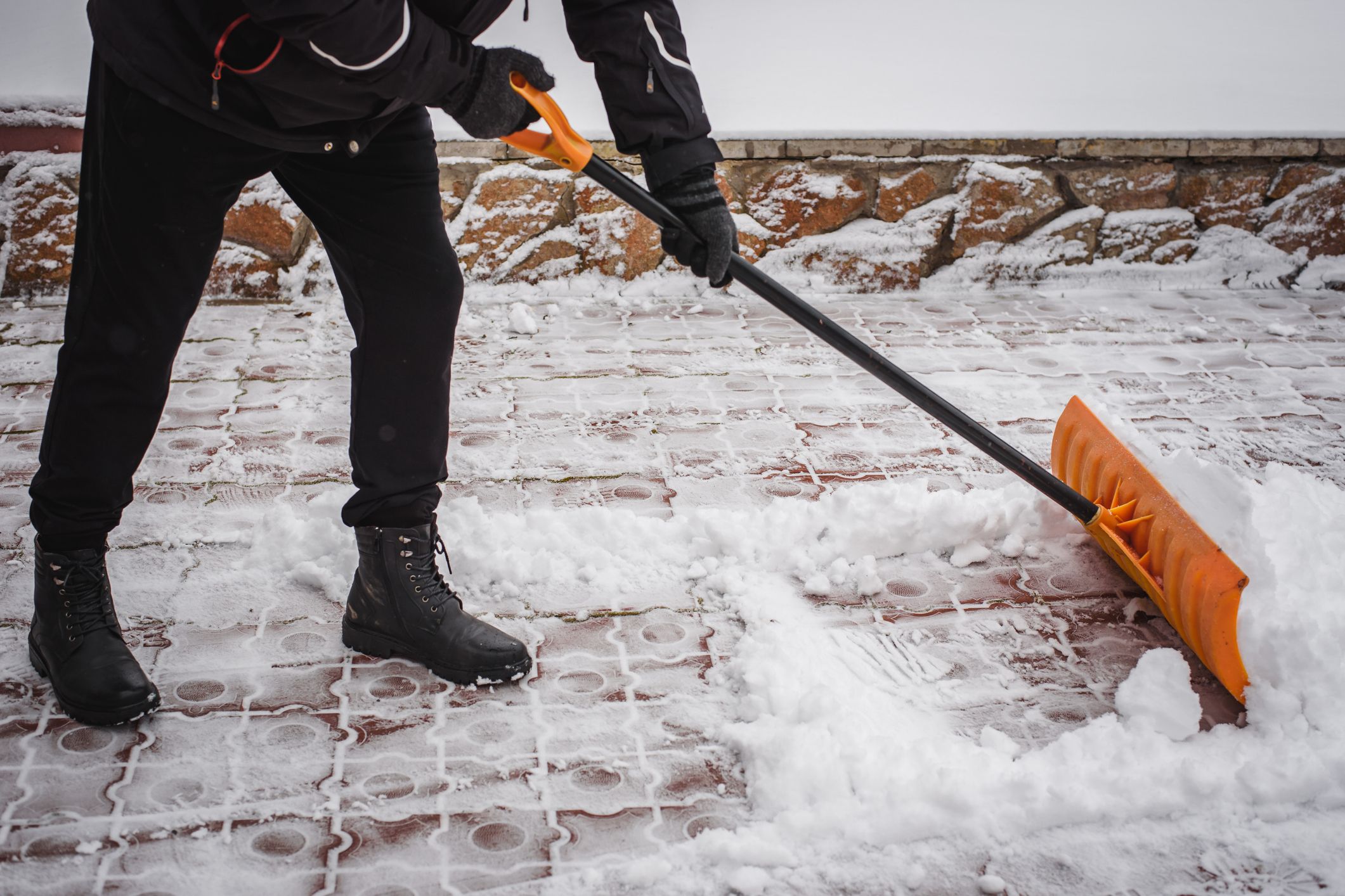 After a snowfall, a person rakes and removes snow in front of his house. Emergency, snowfall