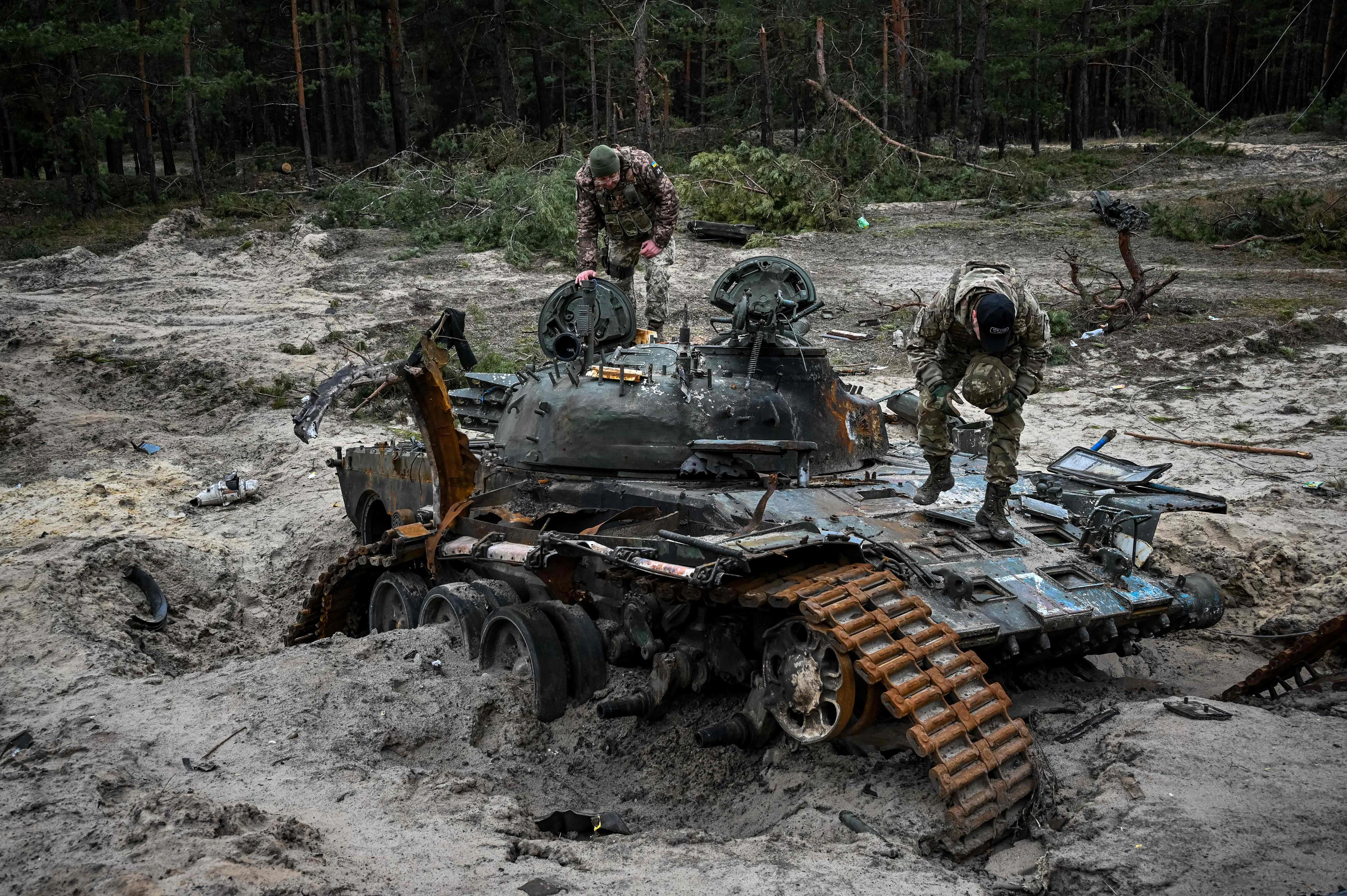 Ukrainische Soldaten inspizieren einen zerstörten russischen Panzer. 
