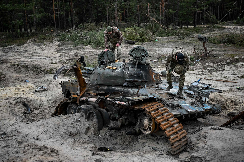 Ukrainische Soldaten inspizieren einen zerstörten russischen Panzer. 