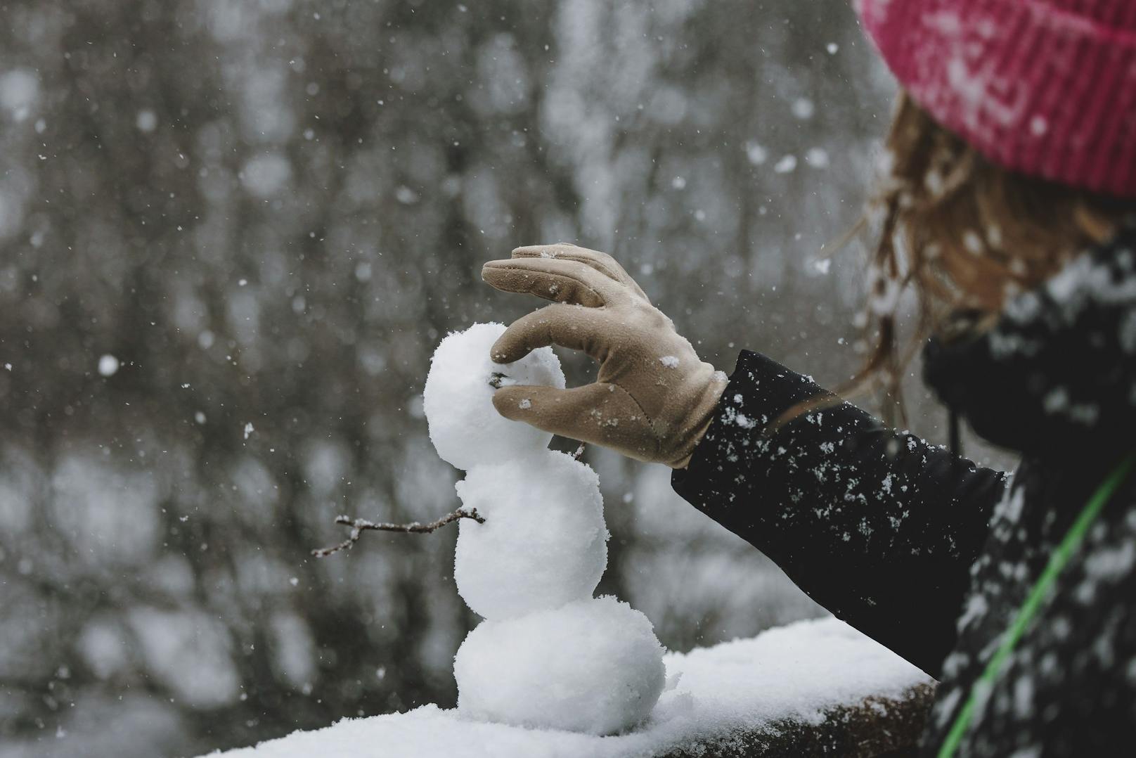 Eine Frau baut einen kleinen Schneemann aus Neuschnee, der am 10. Jänner 2023 in Kaprun gefallen ist.