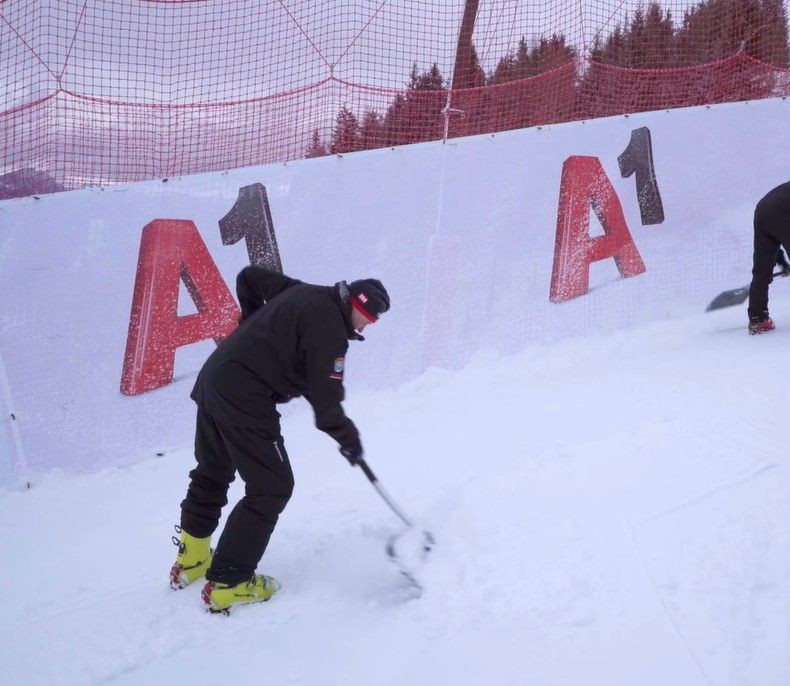 Pistenarbeiter verdichten mithilfe des Neuschnees die Auflage der Streif.