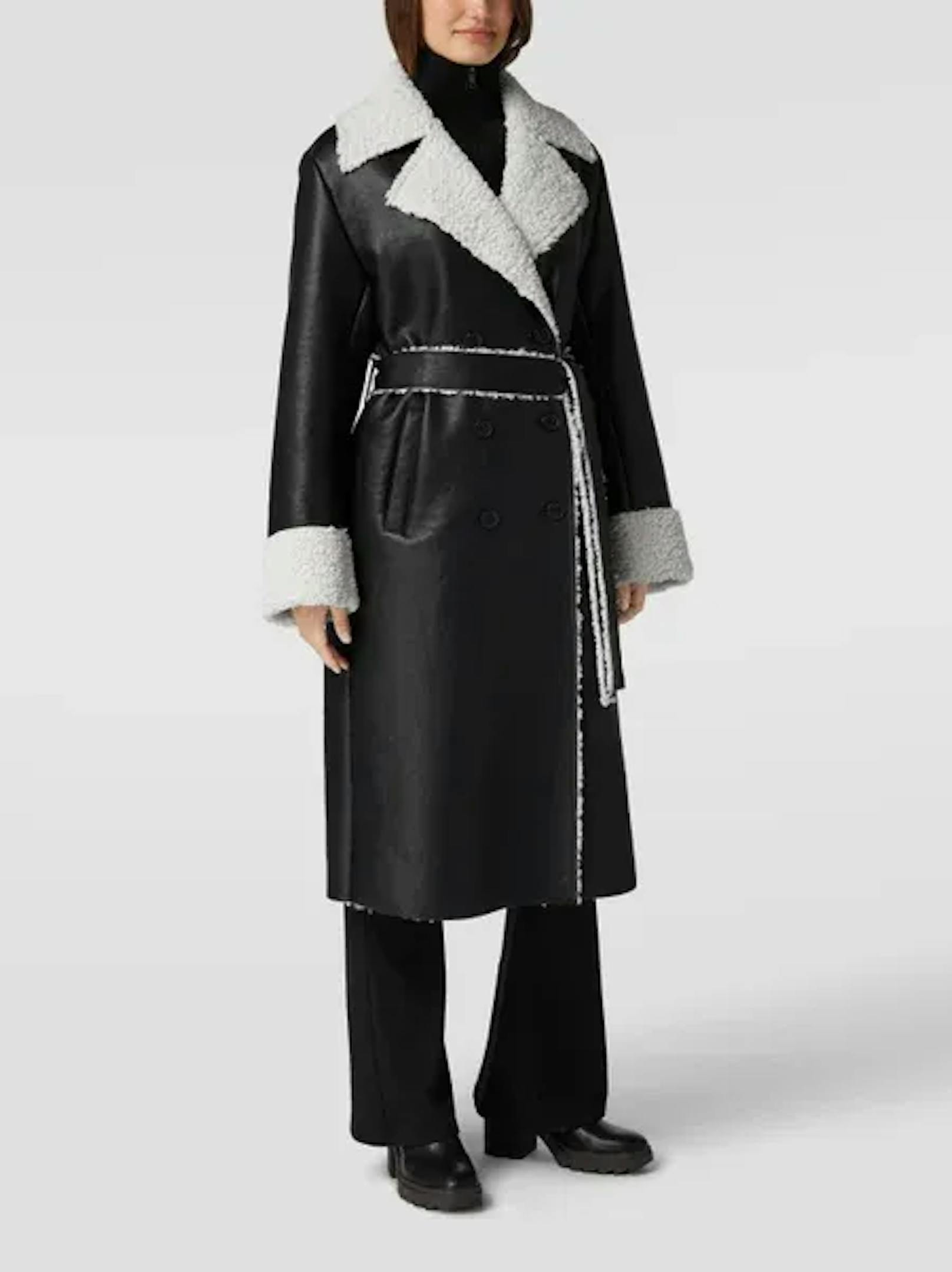 Ein schwarzer Mantel passt zu jeder Bekleidung und sieht mit dem Shearling-Detail an Hals und Ärmel besonders raffiniert aus. 