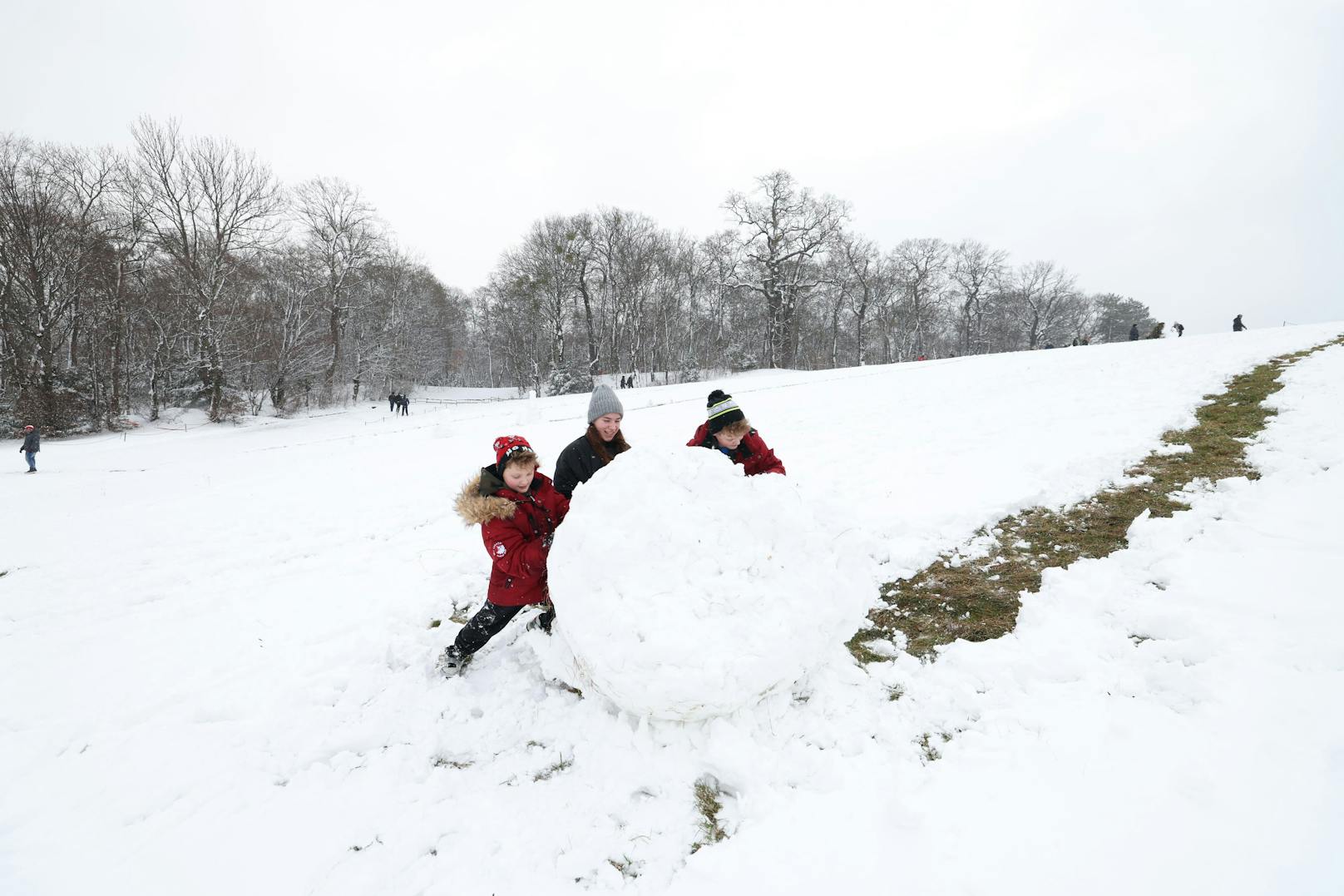 Sonya, Borya und Misha bauen gemeinsam einen Schneemann.