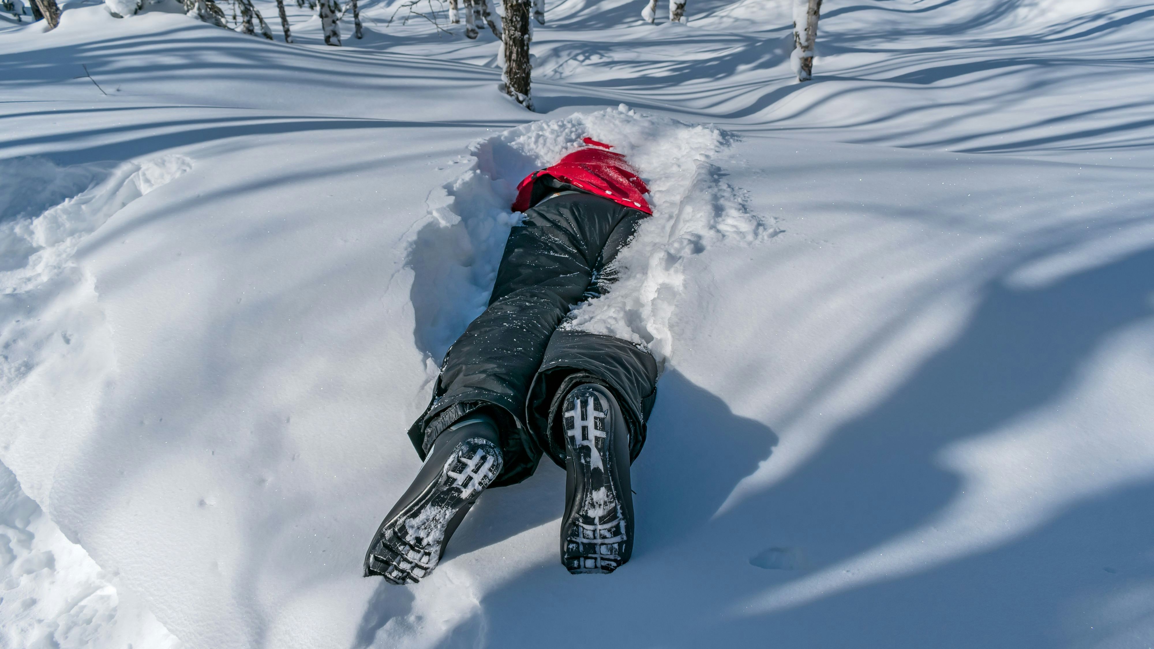 A skier sleeping in a snowdrift, covered with snow, lies among the forest