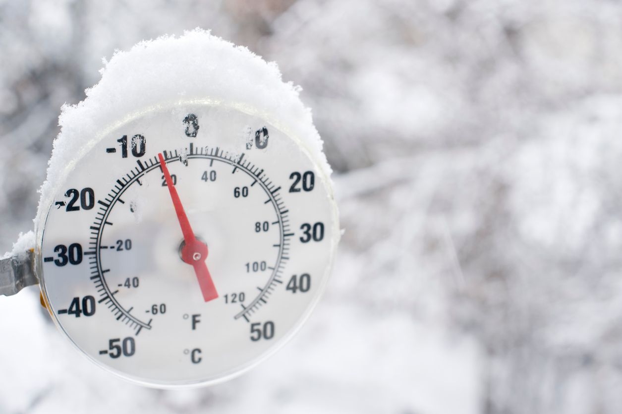 A thermometer showing freezing temperatures and falling snow in Yellowknife, Northwest Territories.  Blurred snow background for good copy space image right.  Close up.
