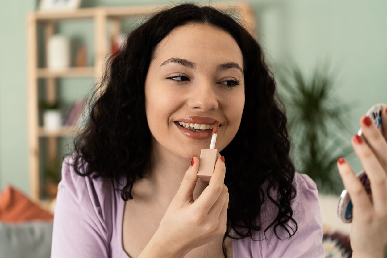 Portrait of a beautiful, young woman putting makeup on her face