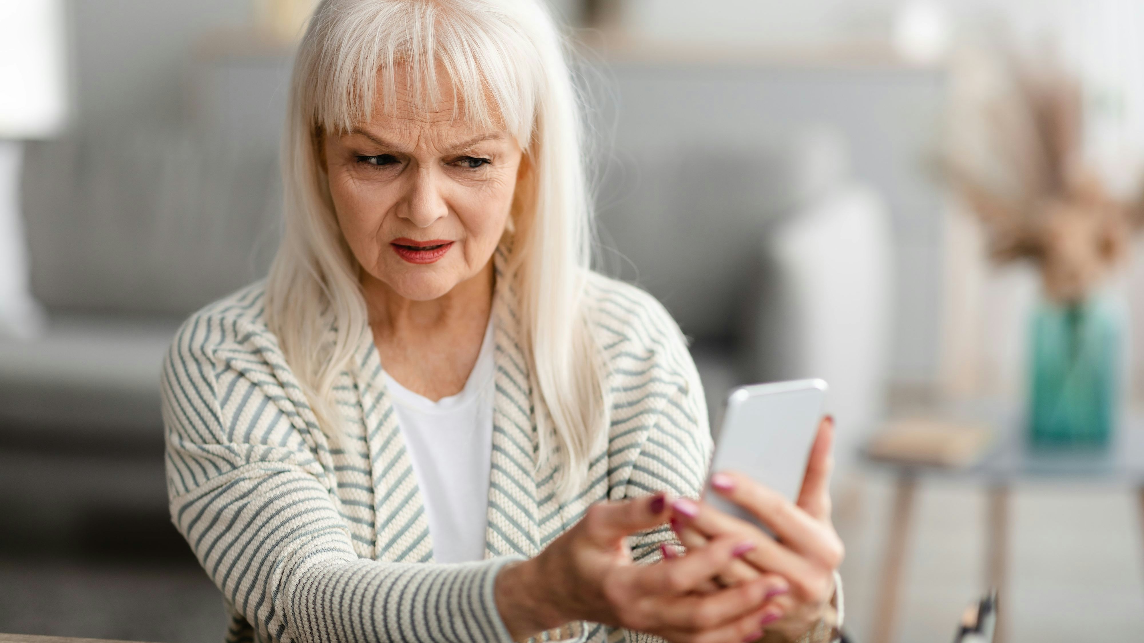 Suspicious Sms. Worried mature woman looking at smartphone screen, received bad news, got fishy scam message, doubtful confused lady holding gadget with concerned face expression, free copy space