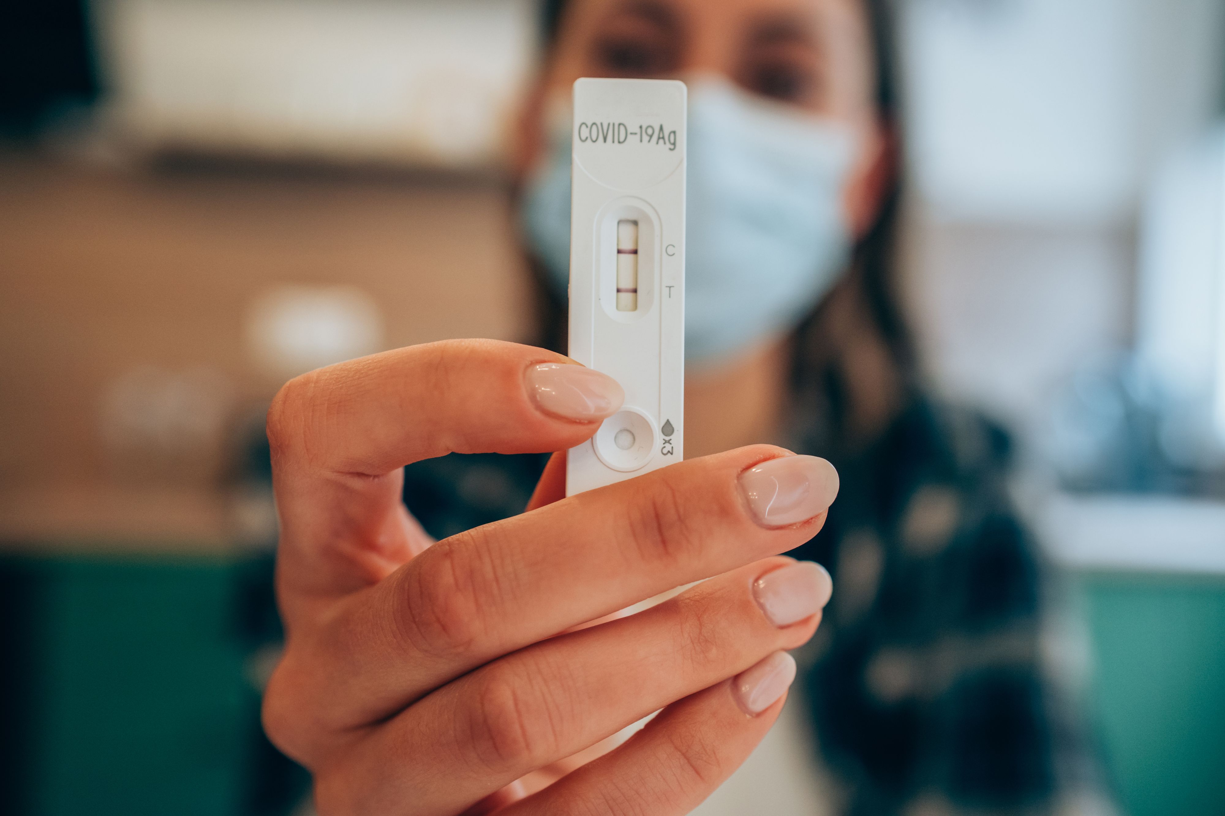 Close-up shot of doctor's hand with protective gloves holding a positive test device to senior patient. Doctor documented the result after a positive test. Doctor hand holding positive Coronavirus/Covid-19 rapid test. Focus is on the test.