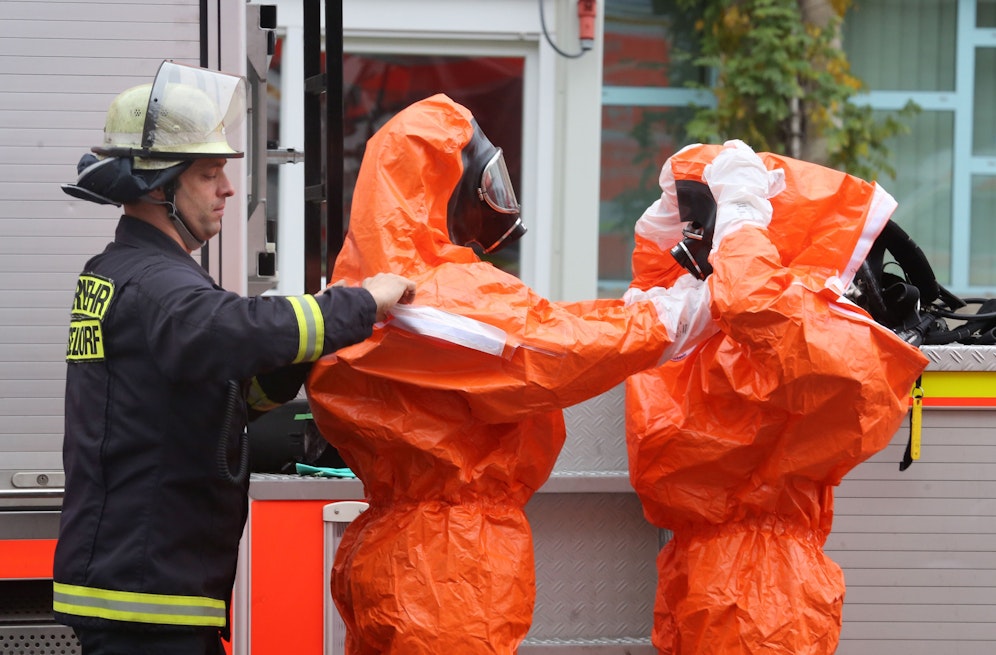 Einsatzkräfte einer Feuerwehr beim Anlegen von Schutzanzügen. Symbolbild.