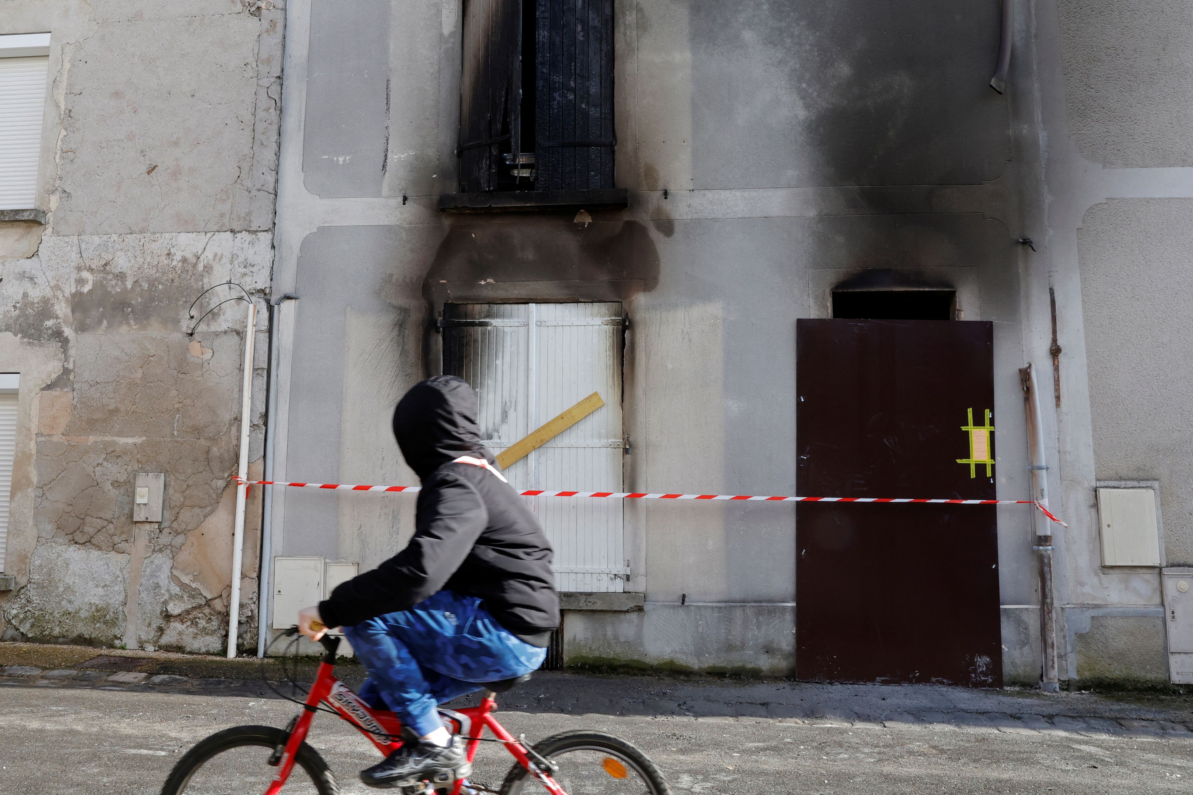 A young rides a bicycle past the house where a mother and her seven children have died in a fire in Charly-sur-Marne, northern France, February 6, 2023.  REUTERS/Pascal Rossignol