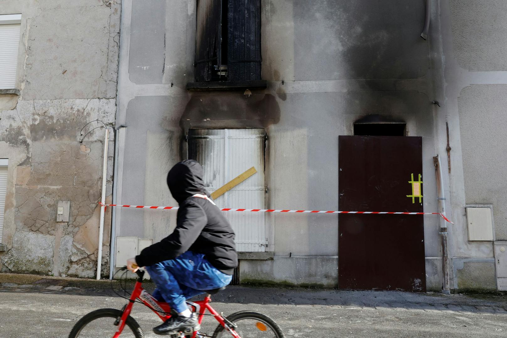 Ein Junge fährt mit dem Fahrrad an jenem Haus vorbei, in dem eine Mutter und ihre sieben Kinder bei einem Brand in Charly-sur-Marne, Nordfrankreich, ums Leben gekommen sind.