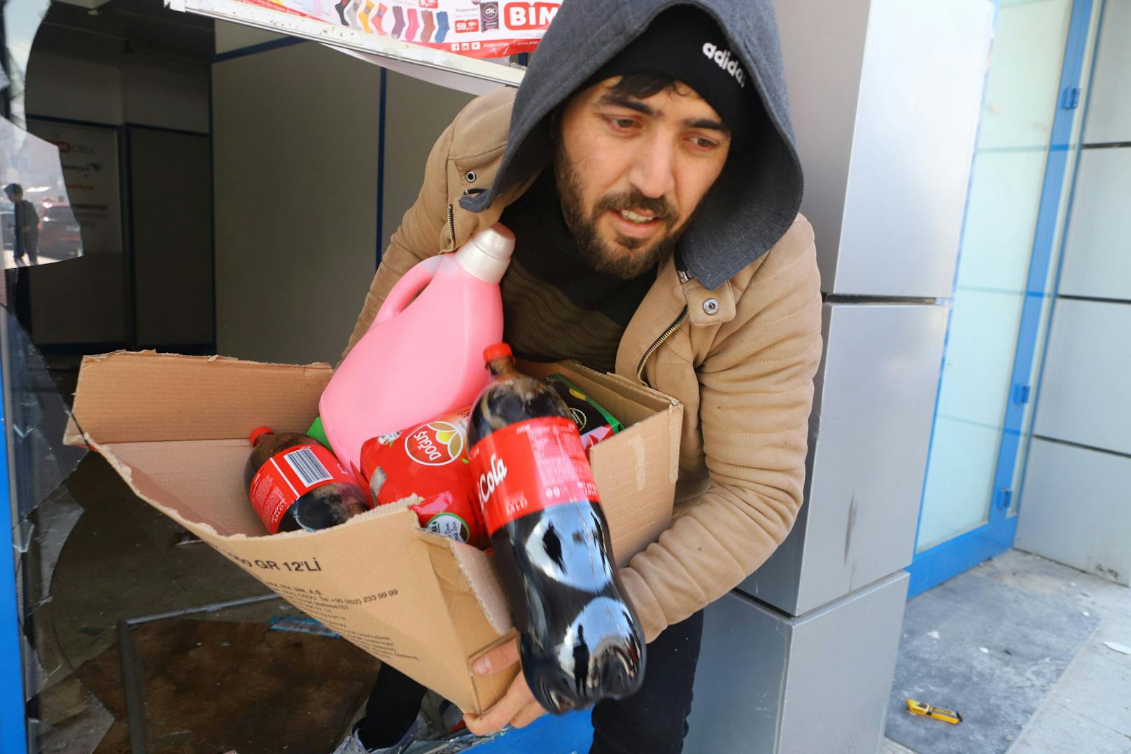 In Iskenderun stürmt ein Plünderer mit Getränken und Essen aus einem Laden.