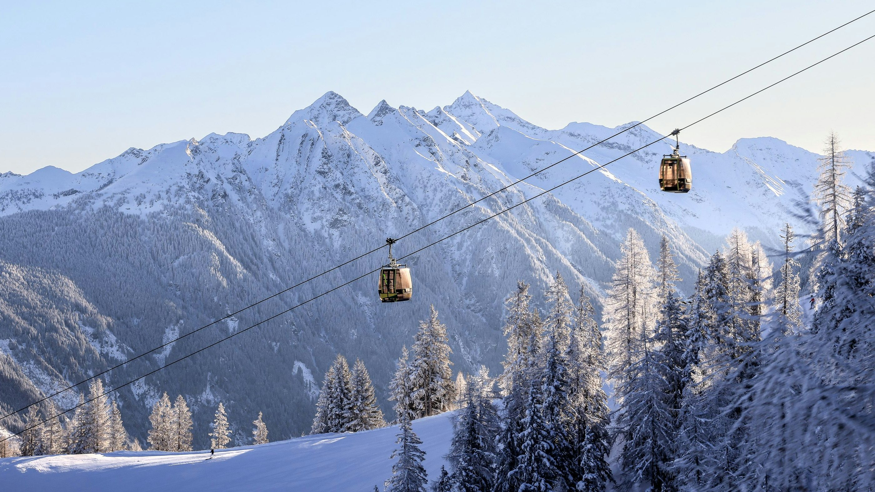 Winter in der Steiermark: zwei Kabinen der Hochwurzen Gipfelbahn oberhalb einer Skipiste mit Blick in die Schladminger Tauern. Aufgenommen am 29. Jänner 2023.