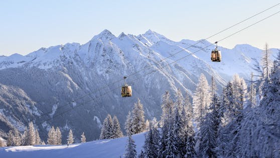 Winter in der Steiermark: zwei Kabinen der Hochwurzen Gipfelbahn oberhalb einer Skipiste mit Blick in die Schladminger Tauern. Aufgenommen am 29. Jänner 2023.