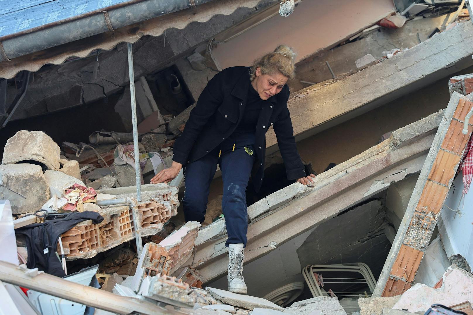 Eine Frau klettert selbständig aus den Trümmern ihres Hauses.