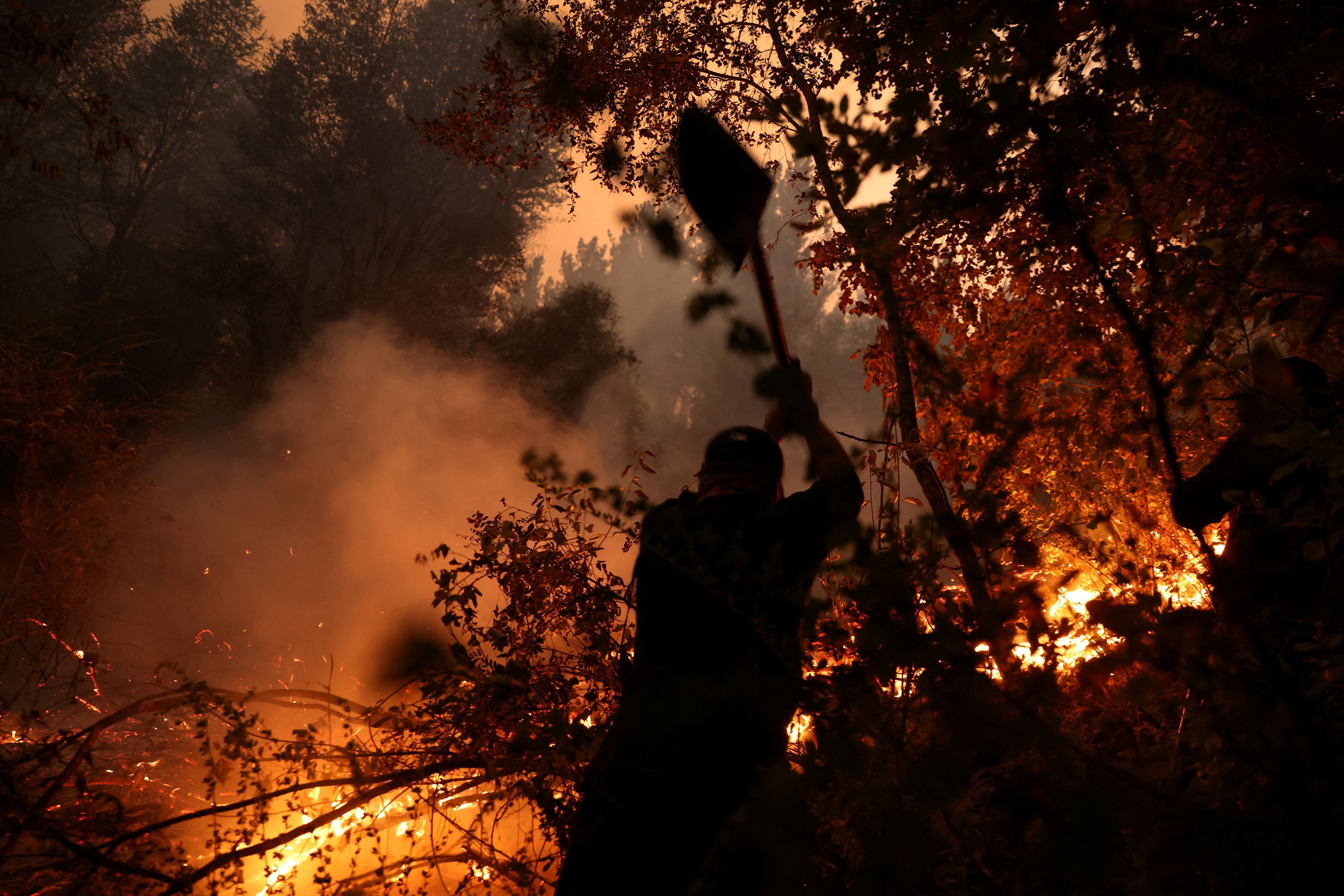 A local resident works to extinguish a wildfire in Nacimiento, Chile, February 7, 2023. REUTERS/Ivan Alvarado